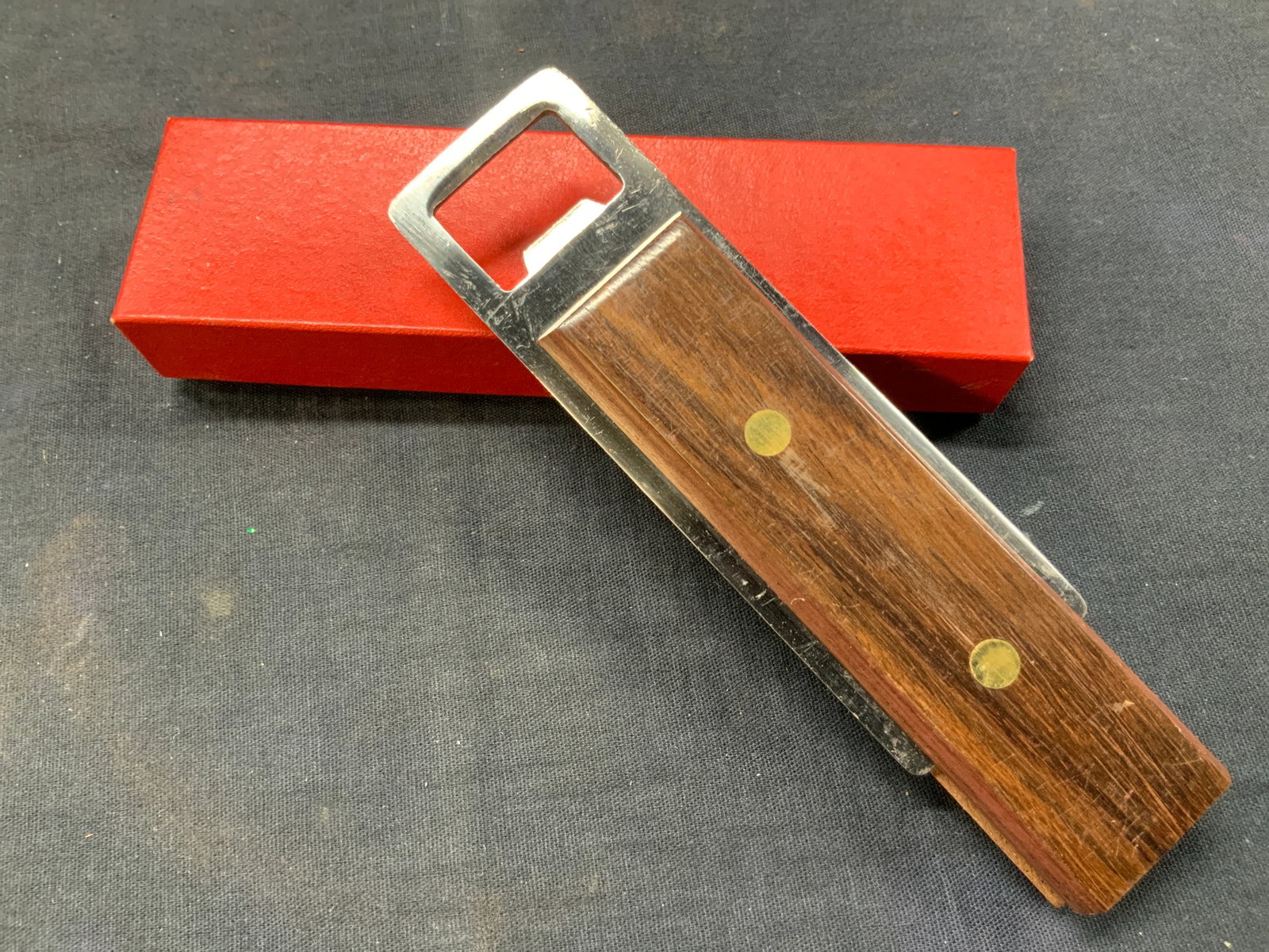 Wooden & Stainless Steel Bottle Opener, Japan: A wooden handles and stainless steel bottle opener, marked made in Japan. Comes in red and white cardboard box, approx 6 inches long and 1.75 inches wide. Box is approx 6 x 2 inches. Moderate wearing 