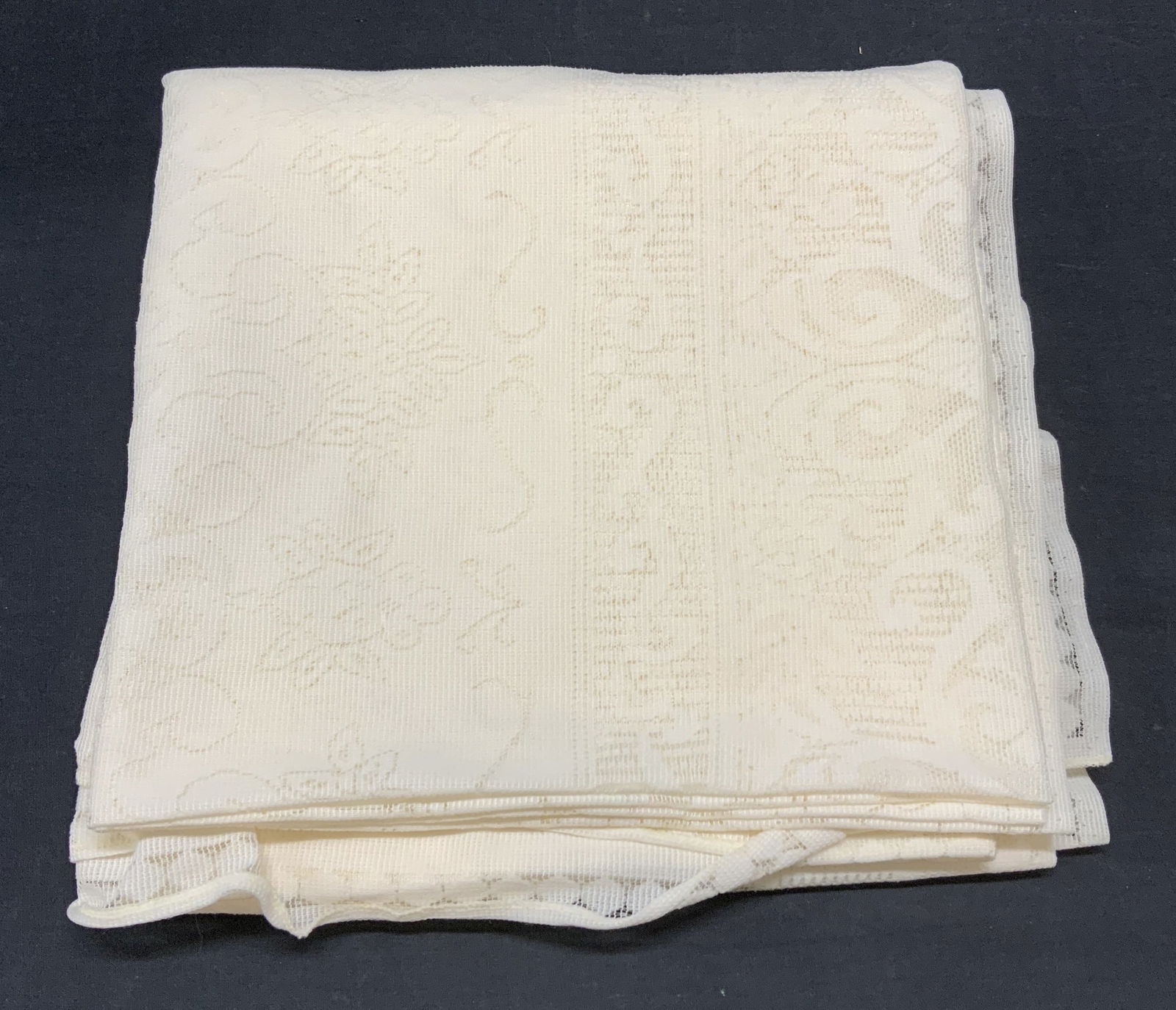 Vintage White Lace Tablecloth: Vintage white lace tablecloth with floral scroll detail. Material feels synthetic. Measures approx. 54 x 54 inches. Wear to material and blemishes observed. Tablecloth, white tablecloth, lace tableclo