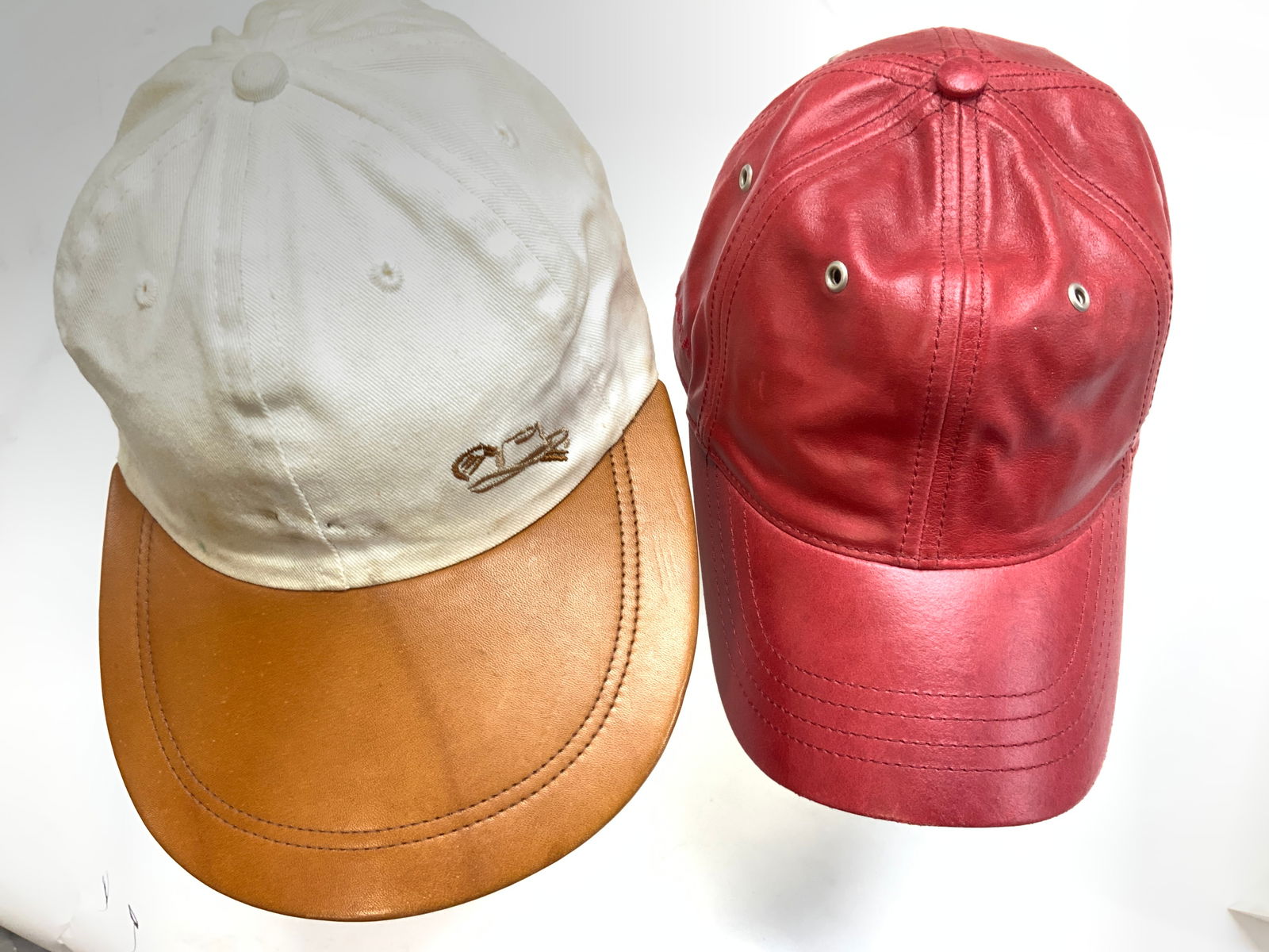 Wilsons Leather, Stetson Golf Caps, 2: Wilsons Leather red leather cap with Velcro on back., curved brim 3 in. Long. One size fits all . 4.25 in cap height. Stetsons Golf Cap. White cotton cap with brown leather brim. Brim measures approx