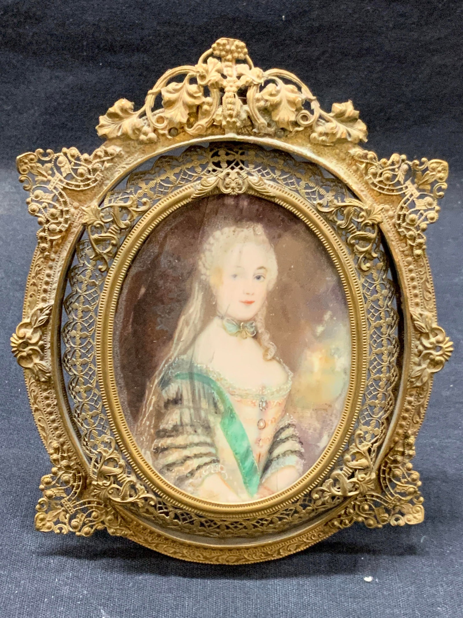 Vtg Hand Painted Portrait In Ornate Brass Frame: Vintage, possibly antique portrait of a woman in 18 century dress with hand applied detailing throughout. Possibly painted on bone. Framed within an ornately crafted brass frame with filigree style ou