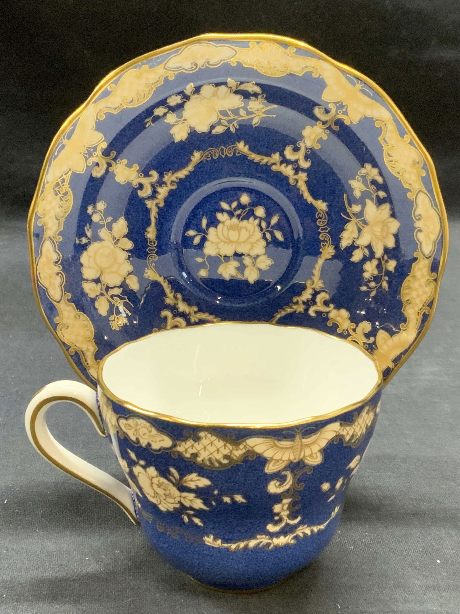 Spode China Gilt Blue Floral Teacup & Saucer: Spode bone china gilt blue teacup and saucer with floral motif. Trademarked to undersides. Made in England. Saucer measures approx. 5.5 inches wide. Teacup measures approx. 3.25 x 2.75 inches. Both pi