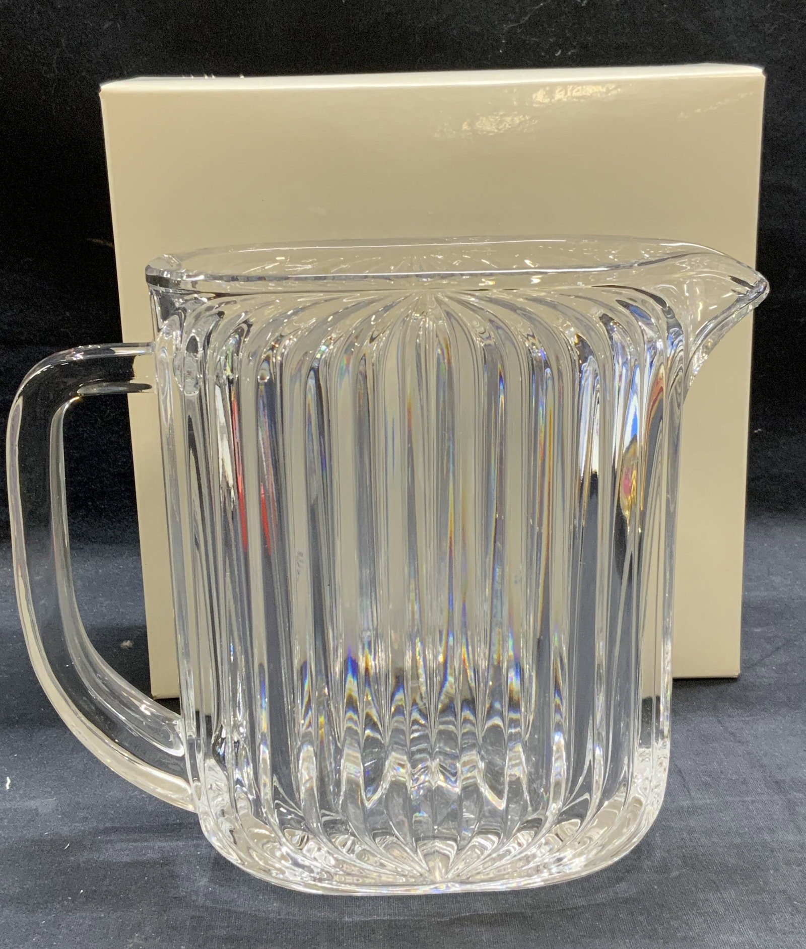 Heavy Ribbed Crystal Pitcher: Heavy crystal pitcher with ribbed motif. Thick walled crystal. Measures approx. 8.5 x 3.5 x 7.25 inches. Includes box. Some surface wear including scratching observed. Pitcher, ribbed pitcher, crystal