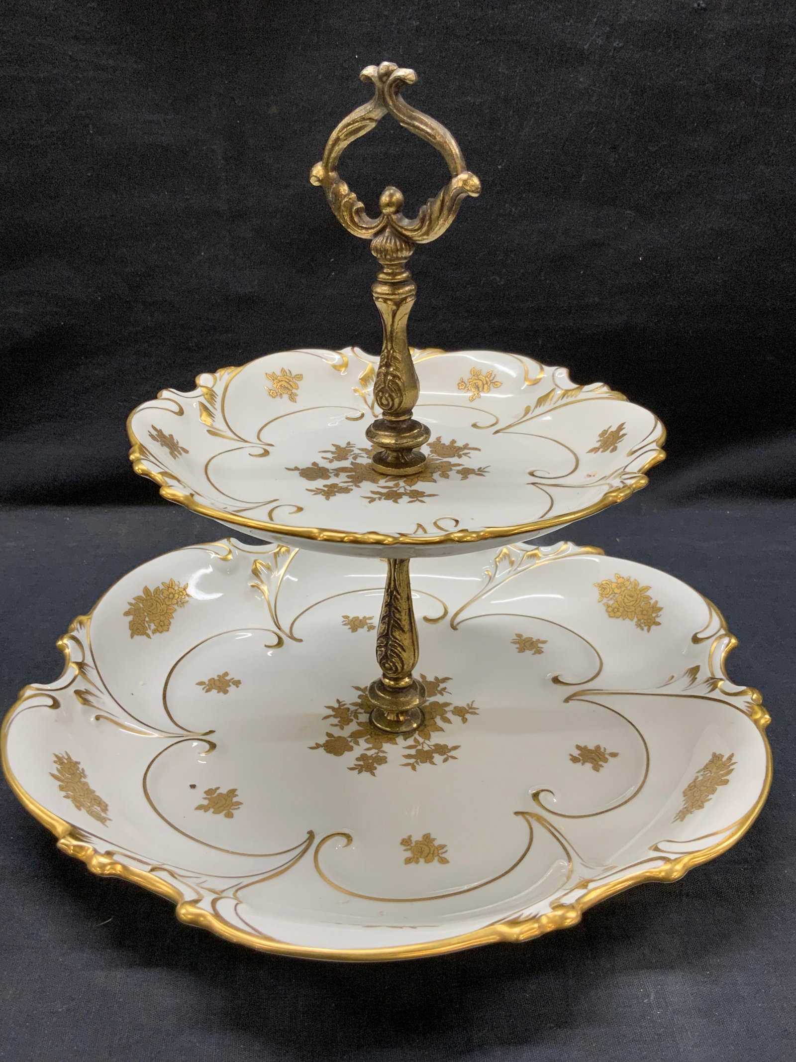 Graf Van Henneberg Porcelain Tiered Platter, GER: Marked on undersides Graf Van Henneberg, made in Germany. A tiered white porcelain dish with gilt rims and gilt floral motifs on centers of dishes with a gilt metal post in ornate art nouveau style. A