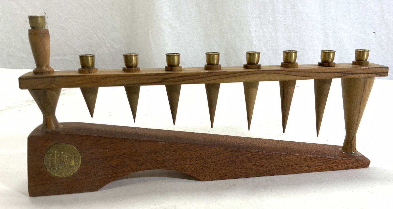 Hand Crafted Wood & Brass Menorah, Israel: Mid century menorah , hand crafted of a lightweight wood and brass candle holders. Sticker label in Hebrew on underside. 2 repaired wood handle holder bases. Measures 11.25 in. Long x 5 in ht. Hanukka