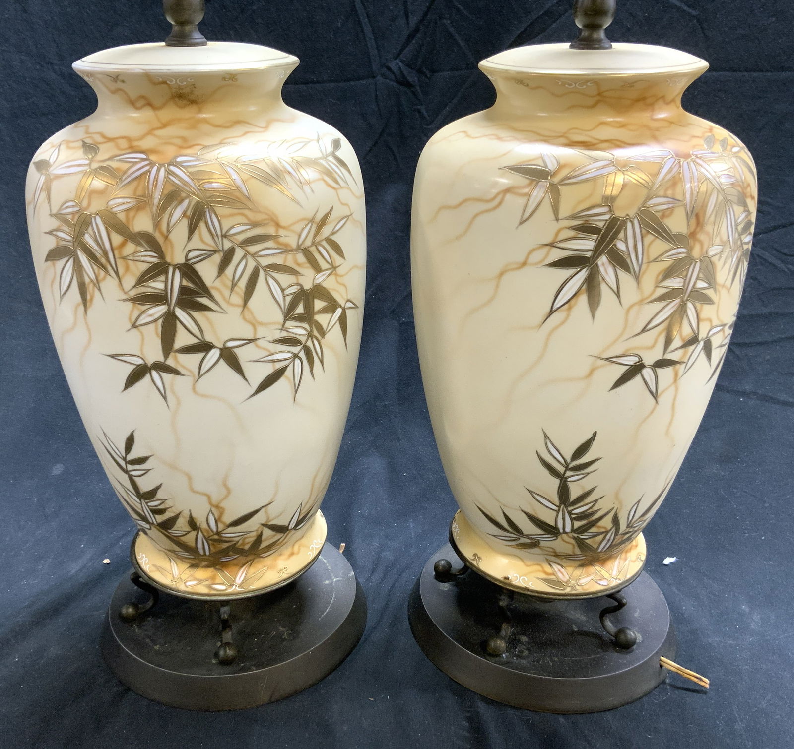 Pair Vintage Porcelain Lamps W Gilt Detail: Lot includes 2 lamps. Each are porcelain with gilt and white toned vine and leaf detail. Lamps include harps. Each lamp has bronze toned circular shaped bases. Lamps each measure approximately 29 inch