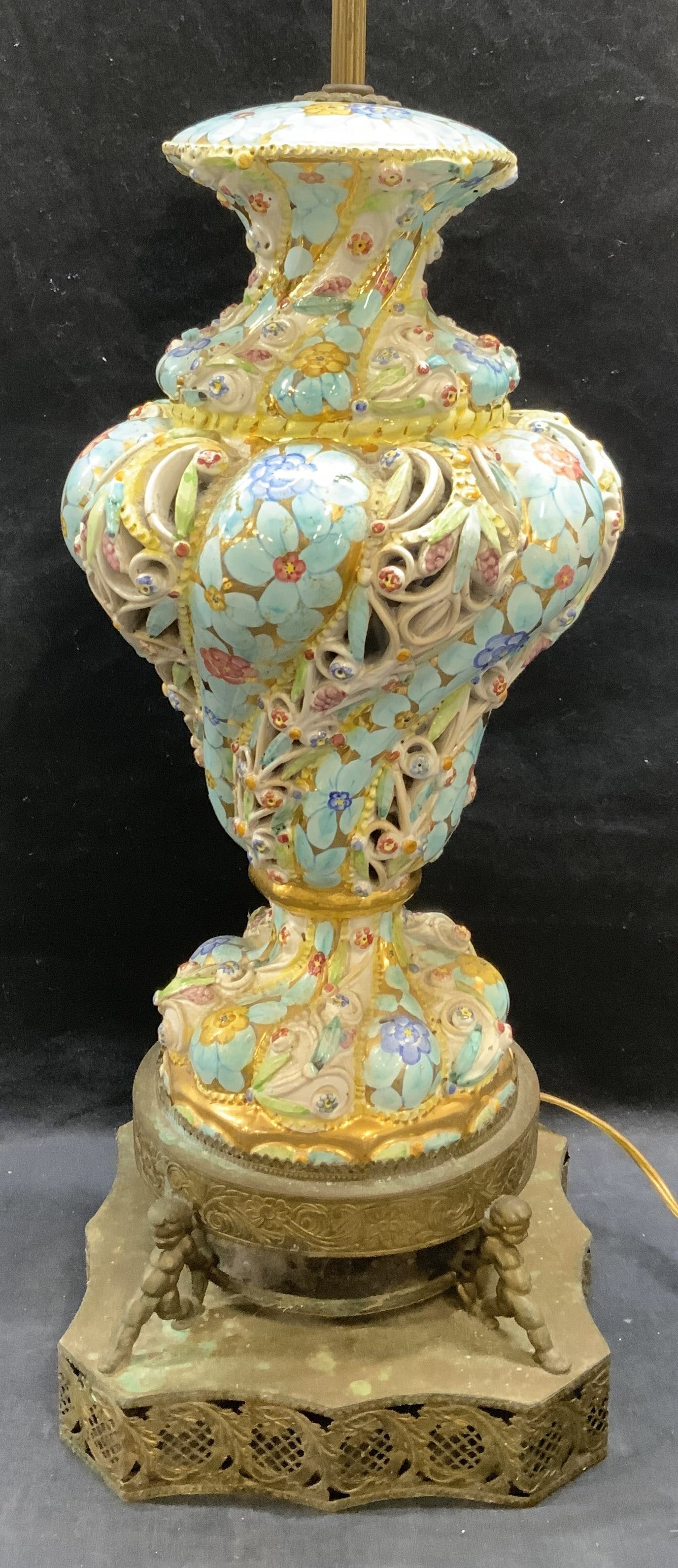 Vintage Hand Painted Porcelain Lamp 20.5 In: Vintage, possibly antique, hand painted porcelain lamp with metal base. Pierced and raised surface with floral motif and gilt decoration. Putti figural detail on base. Measures approx. 9 x 8.5 x 20.5 