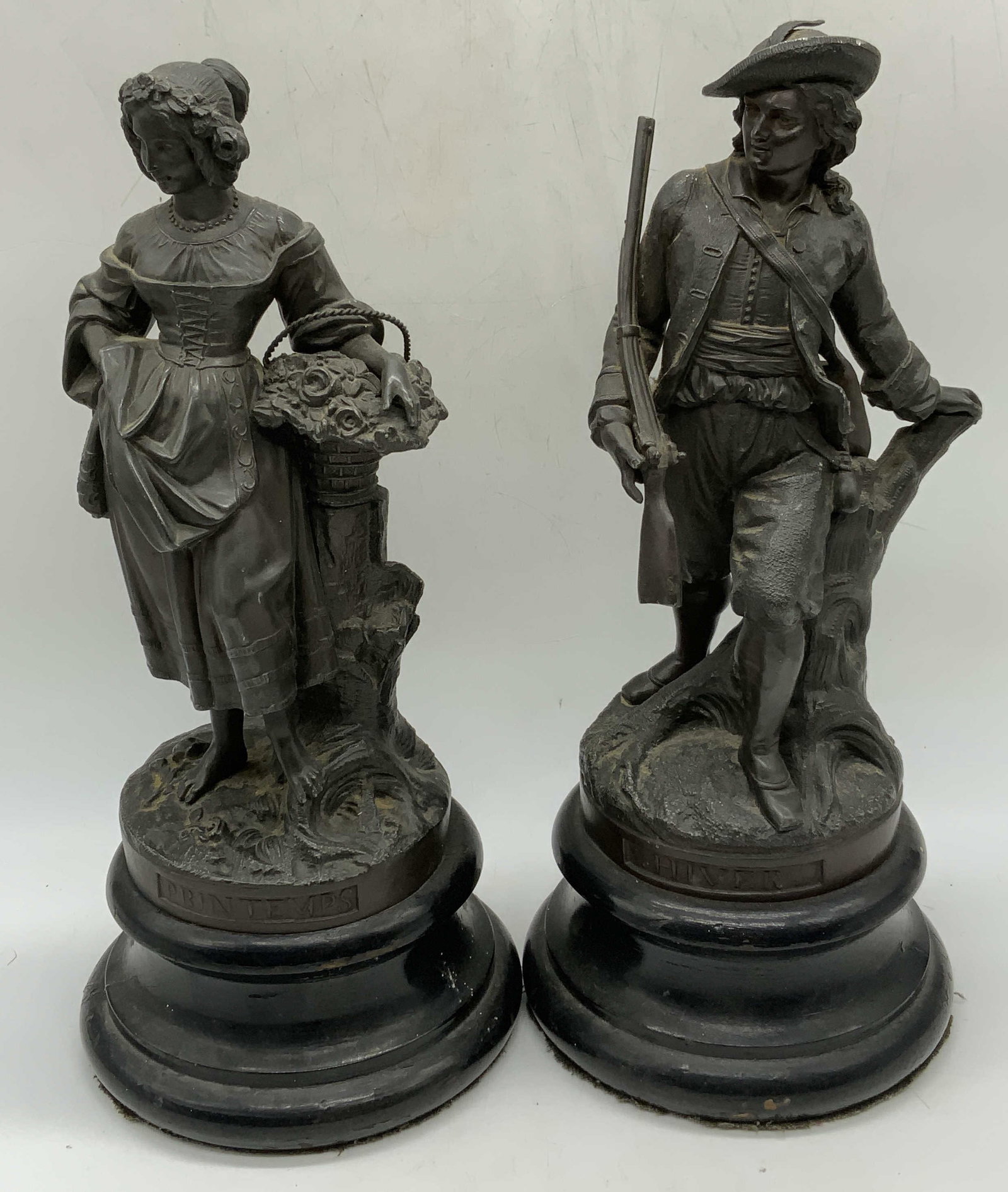 Pair Vtg Winter & Spring Cast Metal Figurals: Pair of vintage cast metal winter and spring Figurals. Marked Hiver with figure of a man and rifle and Printemps with figure of a woman and flowers. Wood bases. Measure approx. 5.75 x 12.75 inches eac