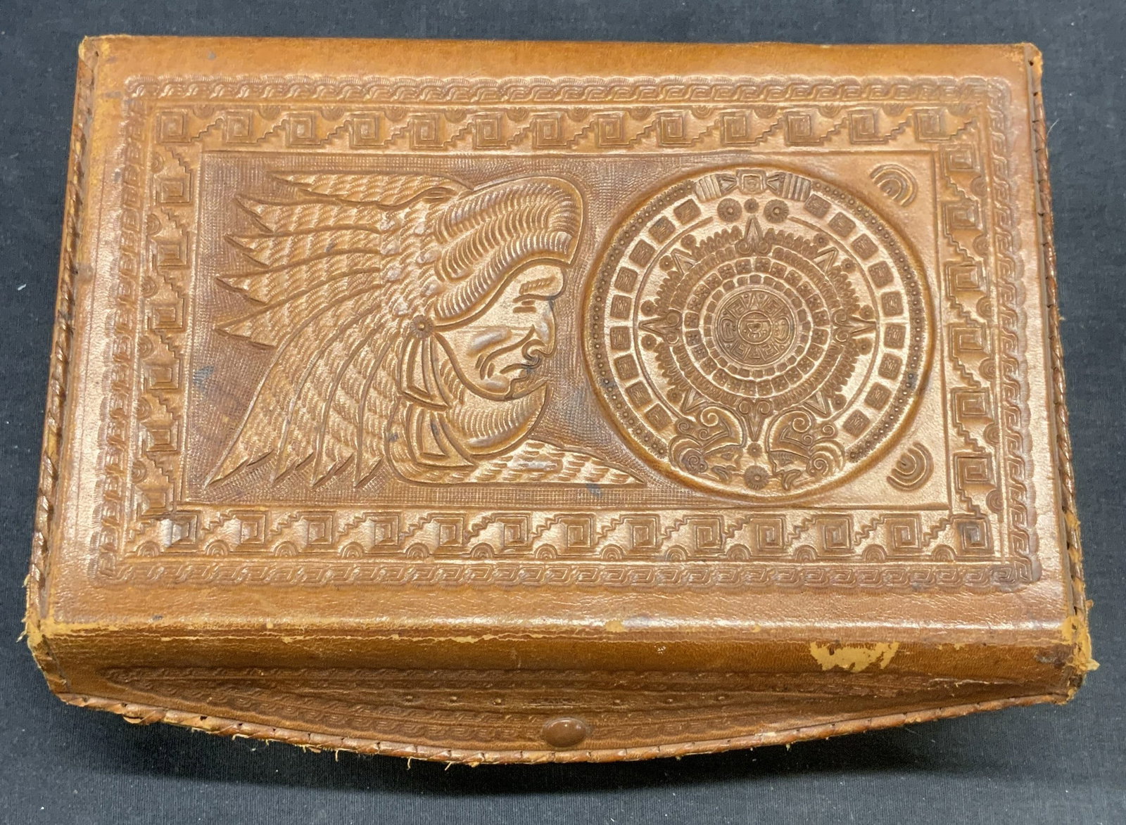 Vintage Figural Leather Jewelry Box, Mexico: Vintage tan leather jewelry box with figural Native American head and scroll motif. Marked Mexico. Red velvet lined interior. Measures approx. 9.5 x 6 x 3 inches. Surface wear including scratching and
