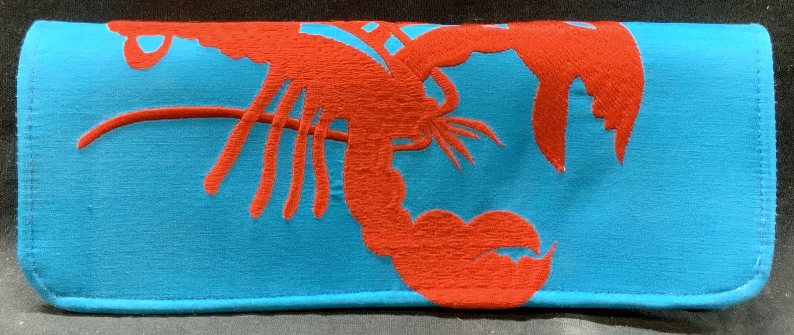 Shiraleah Embroidered Silk Lobster Clutch: Marked on tag Shiraleah. A blue toned clutch with embroidered red lobster on exterior with a red silk interior. Approx 10 x 4 x 0.75 inches Minor pulling to threading due to age and use Silk lined clu