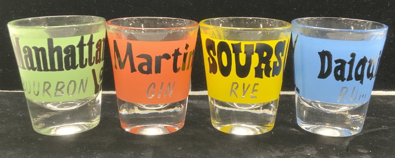 Set 4 Recipe Shot Glasses, Martini, Daiquiri +: Set of 4 shot glasses, each with a different mixed drink name and recipe in stenciled colors of green, coral, blue, and yellow. Manhattan with bourbon. Martini with gin. Sours with rye. Daiquiri with 