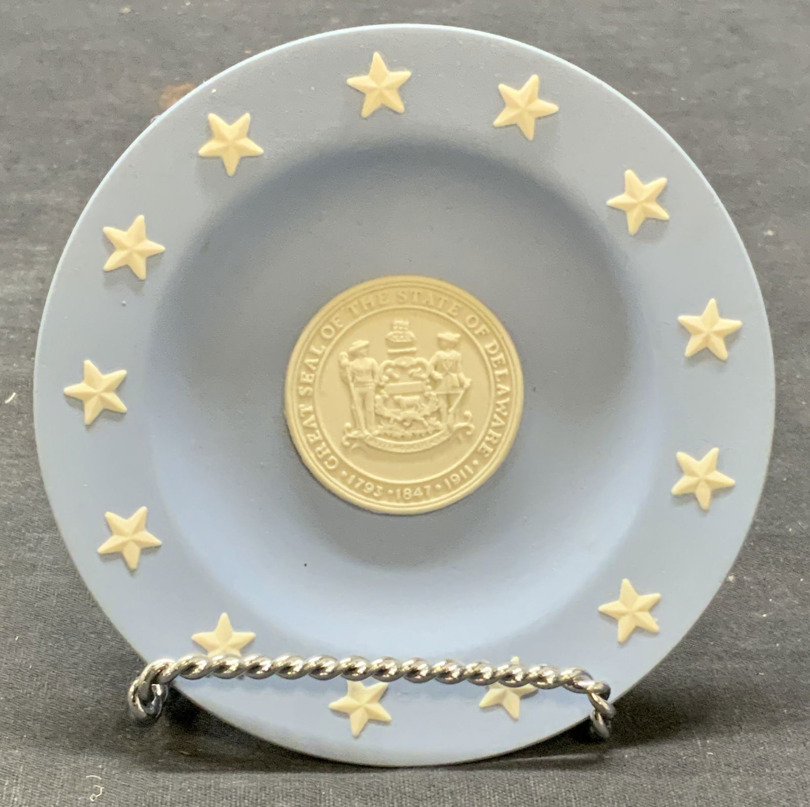 Wedgwood Seal of Delaware Jasperware Plate: Wedgwood blue Jasperware late with raised white bas relief. Seal of the state of Delaware to center with star motif border. Trademarked to underside. Made in England. Measures approx. 4.25 inches diam