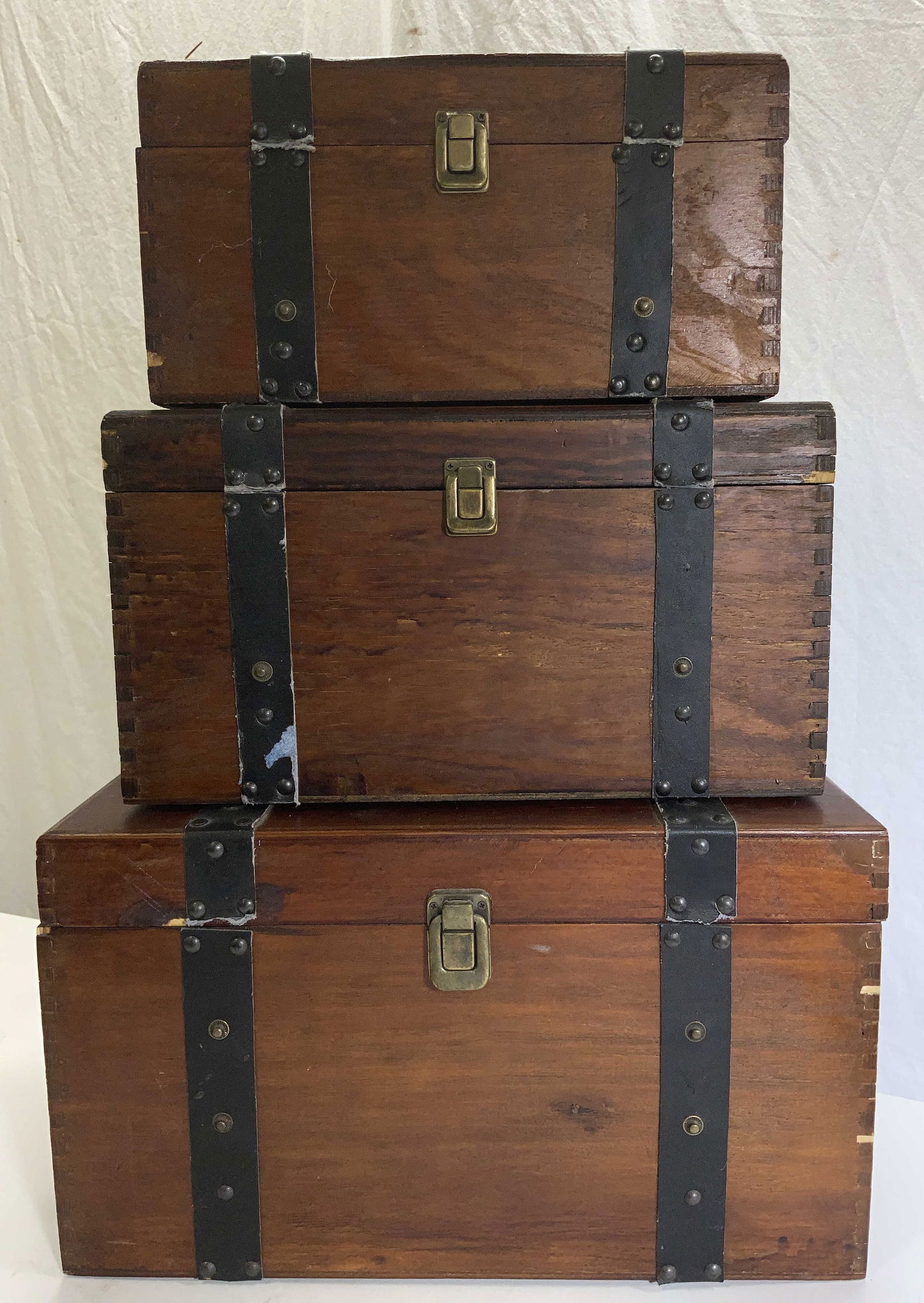 Set 3 Hand Crafted Wood Nesting Chests: Hand crafted wood chests with black fabric affixed with metal rivets. All chest have hinged tops, cast iron or aluminum carry handles, brass latches, and have wine color velvet interior. Tongue and gr