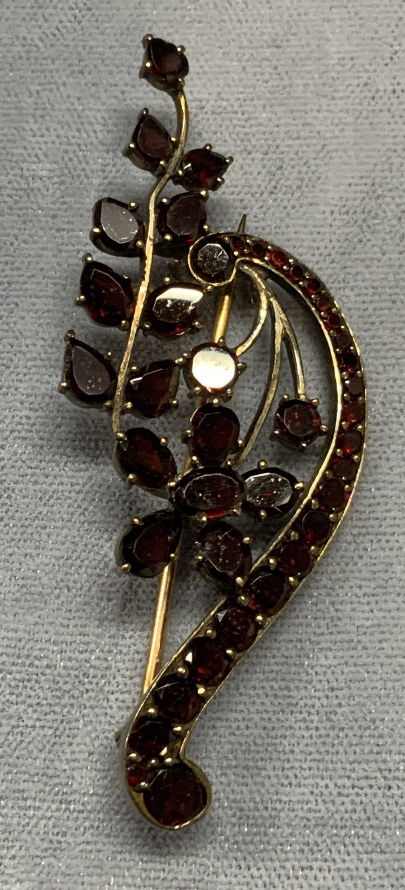 Vintage Gold Tone Garnet Flower Brooch: Vintage gold tone brooch with red garnet gemstone and flower motif. Hinge pin to underside. Measures approx. 2.5 x 1 inches. Some surface wear including scratching observed. Estate jewelry, costume je