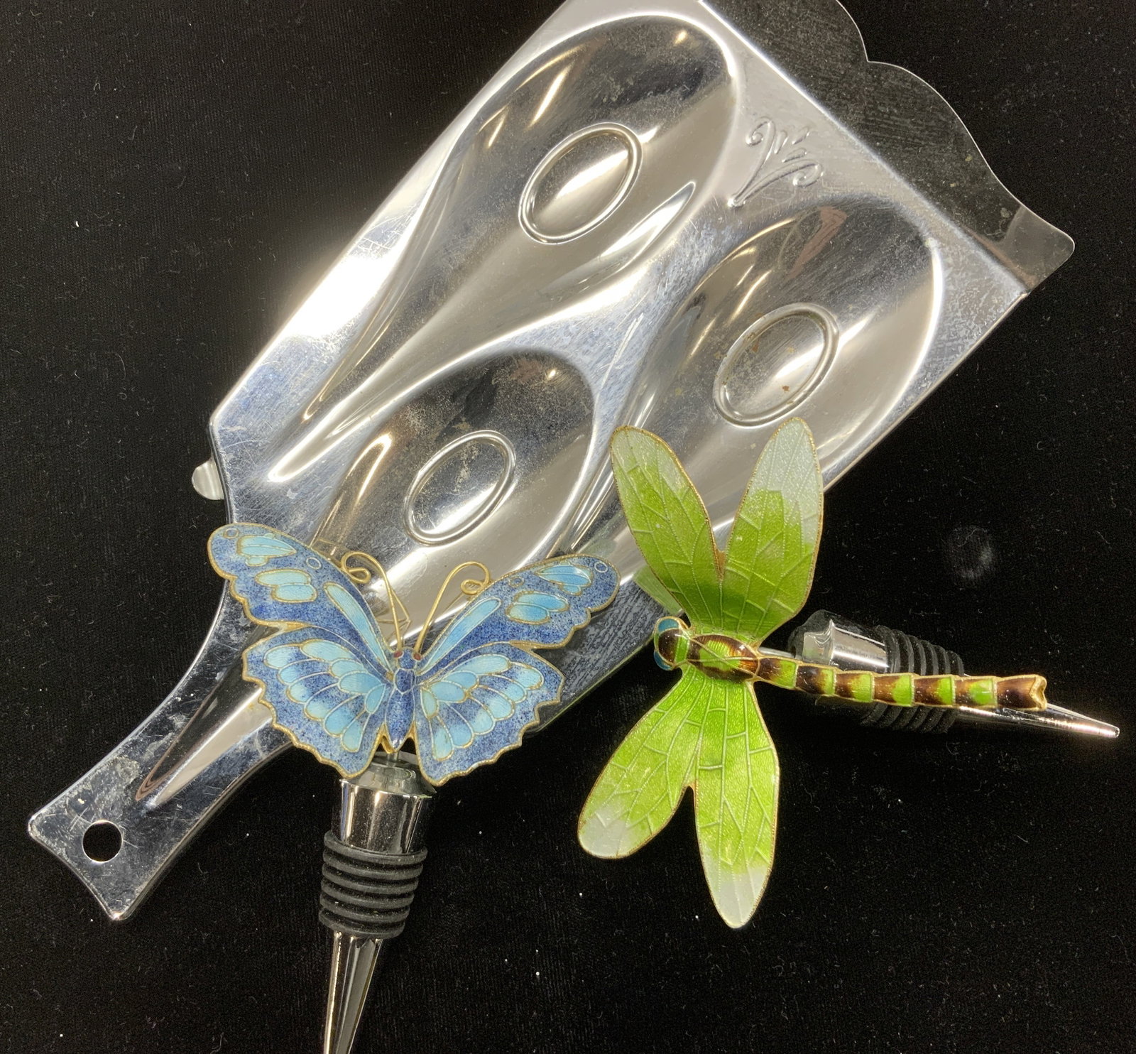 3 Kitchenware, Spoonrest & Insect Wine Corks: 3 wine corks with decorative enamel dragonfly for butterfly figural. Light Wear to exterior insect metal. Corks are a heavy chrome with rubber seal. Measure 4 x 4 in. Metal spoon rest, 4.75 x 9.75 in.