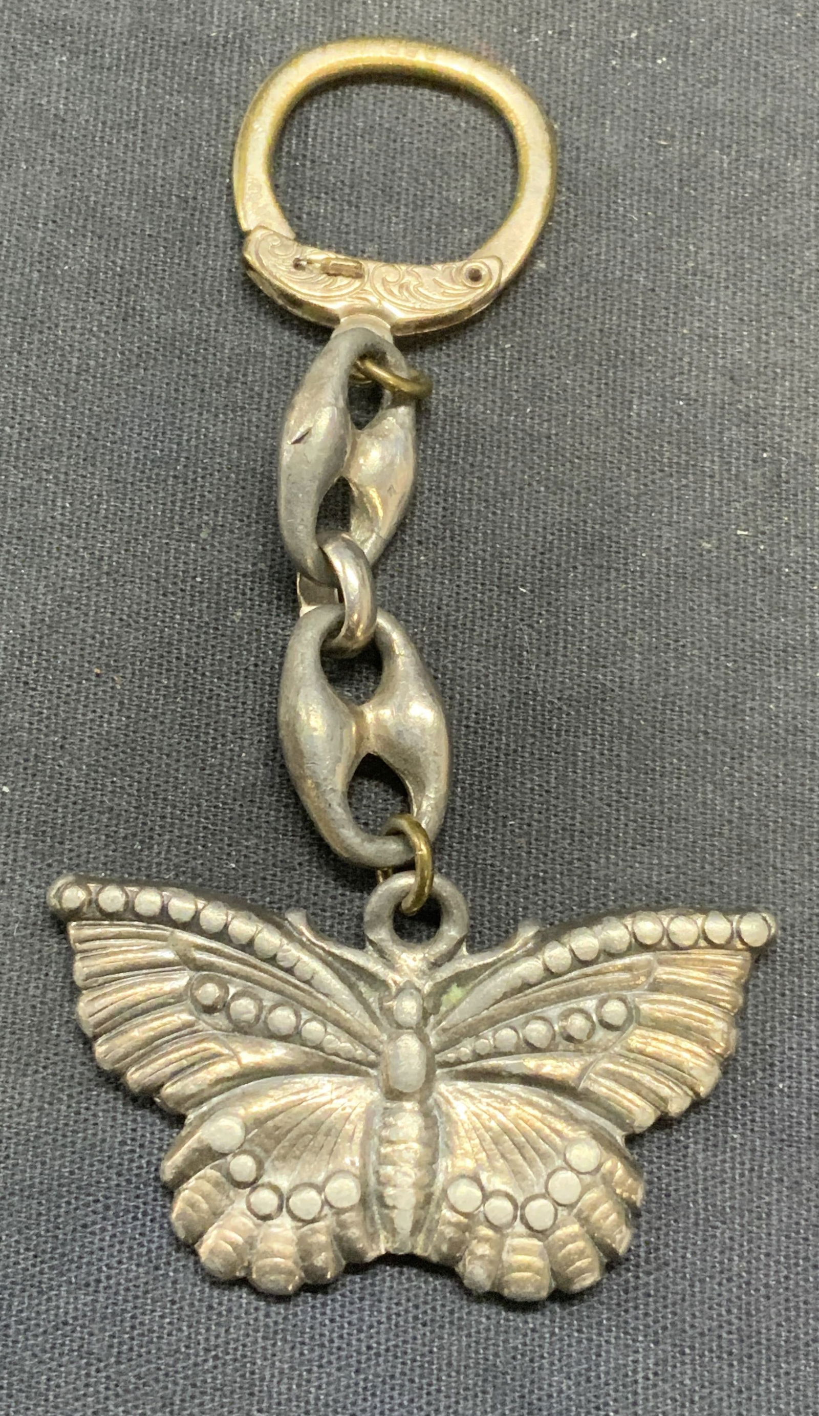 Vintage DBP Silver Tone Butterfly Keychain: Vintage silver tone keychain with butterfly motif pendant. Marked DBP on ring. Pendant measures approx. 2 x 1 inches. Some surface wear including scratching observed. Estate jewelry, costume jewelry,