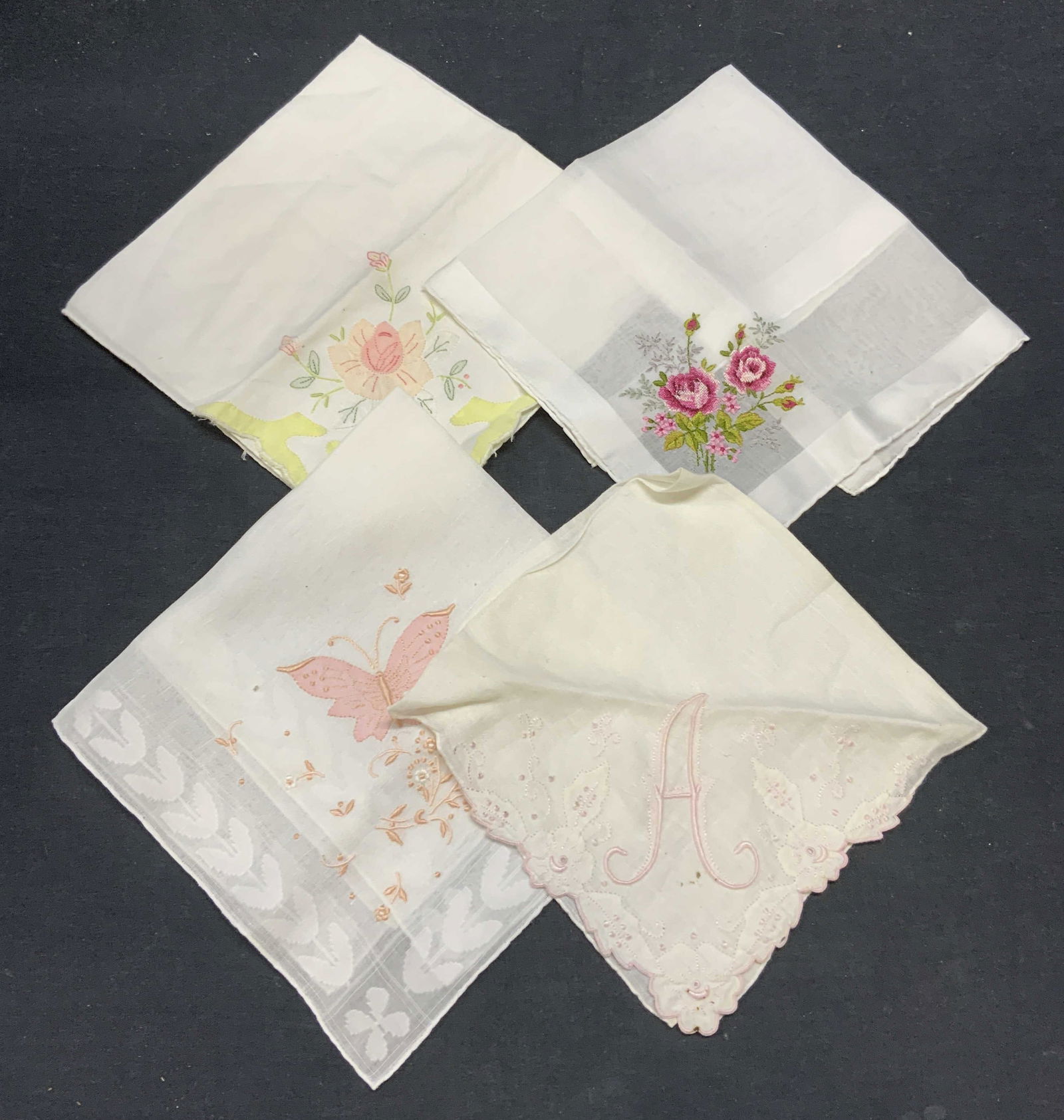 Lot 4 Vintage Cotton Floral Handkerchiefs: Lot of 4 vintage white cotton handkerchief with embroidered floral, butterfly, and monogram A motifs. Largest handkerchief measures approx. 15.5 x 15 inches. All pieces have some wear to material cons