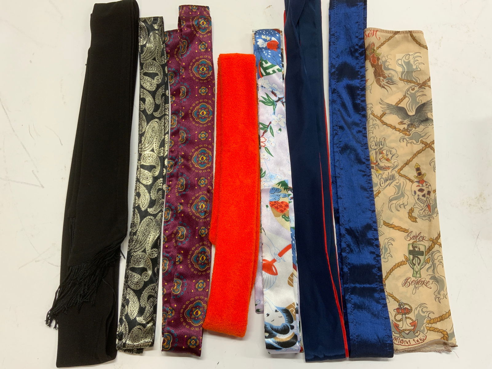 Group9 Tie Belts and Avant Guard Pirate Arm Sleeve: Group of 8 satin Polyester robe or dressy tie belts, including an orange terry cloth belt. Longest belt is red and blue belt, measures 78 in. Long. Black evening fabric belt with tassels measures 70 i