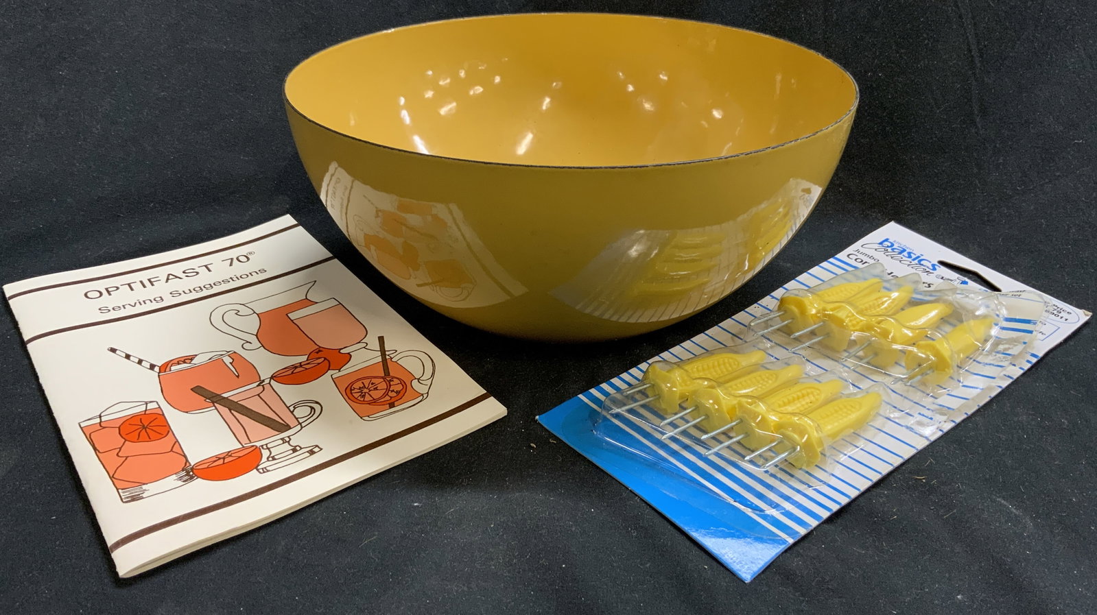 Lot 3 Vtg Enameled Bowl Corn Holders & Optifast Bk: Lot includes 1 yellow toned enameled bowl, 1 package of 8 KITCHEN BASICS COLLECTION corn holders, & 1 Optifast 70 Serving Suggestion Book. Bowl measures approximately 9 inches diameter 4 inches tall. 