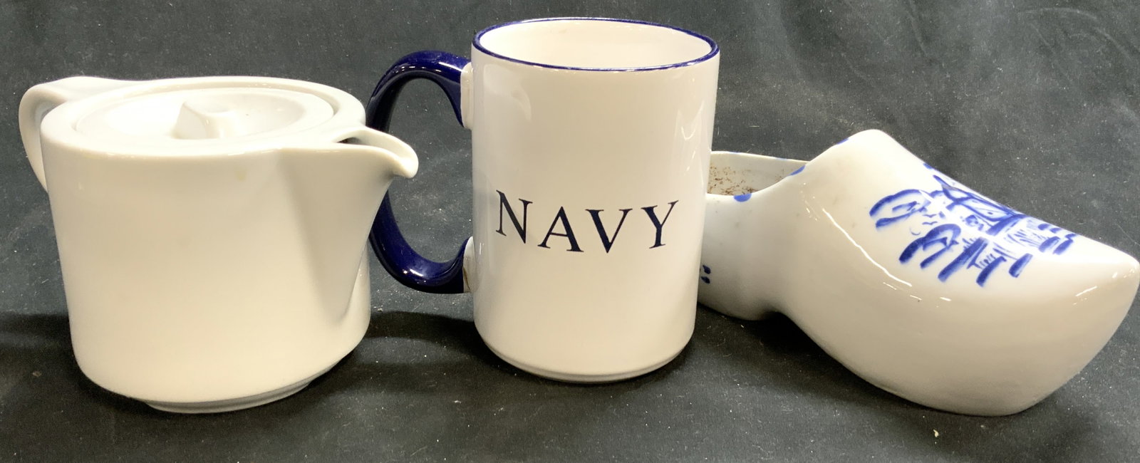 Lot 3 Porcelain Mug, Pitcher & Clog Planter: Lot Includes 1 clog form planter, 1 mug which reads NAVY, Underside marked M WARE, & 1 pitcher with lid marked Pillivuyt. Each piece is porcelain. Mug measures approximately 4.5 inches tall 5 inches d