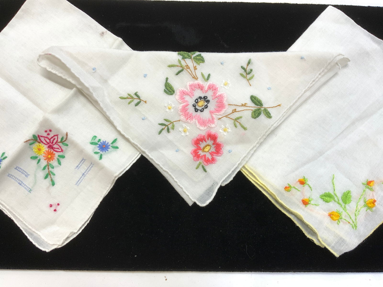Group 3 Hand Embroidered Cotton Hankies: Floral cotton hankies that re hand embroidered. Vintage . On White cotton . Measure 10.5 x 9 in. ( yellow flowers); hand rolled with pink flowers measure 11.5 x 11.25 in. Multi color floral hankie wit