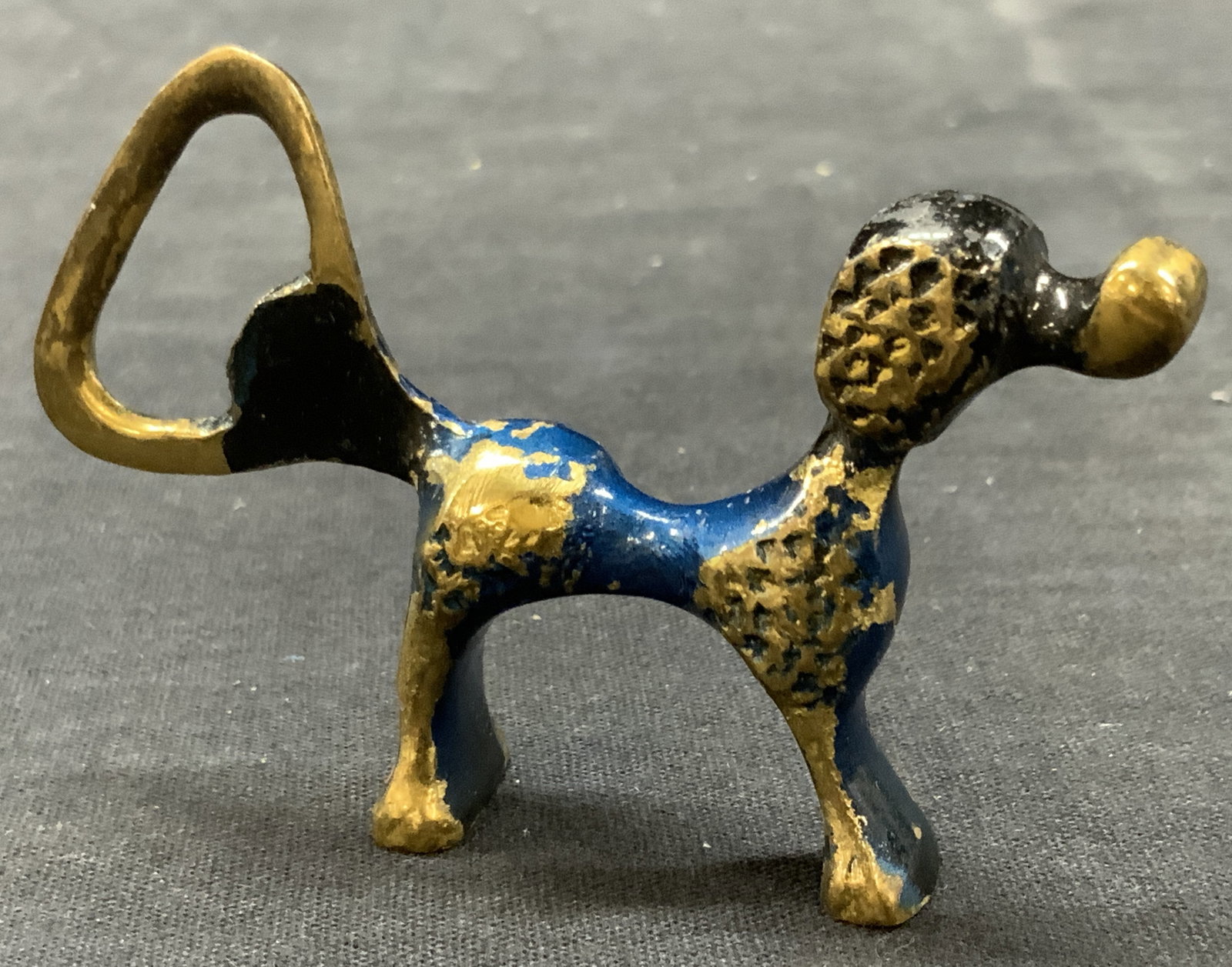 Vtg Brass Poodle Bottle Opener: Vintage brass made enamel bottle opener in the shape of a poodle dog with the tail being the bottle opener. Approx 2 inches tall and 3 inches long. Evident losses to enamel and wearing to brass. Vinta