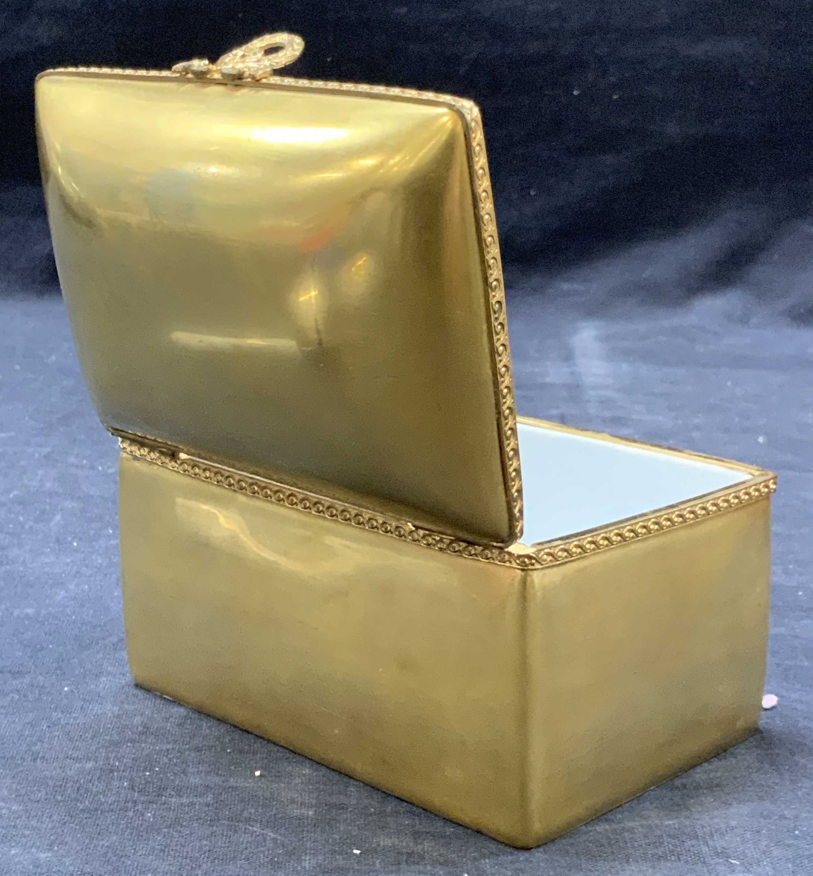 Limoges Gilt Porcelain Trinket Box, France: Porcelain trinket box with braided frame and reef latch. Marked on underside, Limoges France. Box is adorn in gold gilt approx 3 x 4.24 x 3.25 inches Moderate wearing to gilt on edges and corners and 