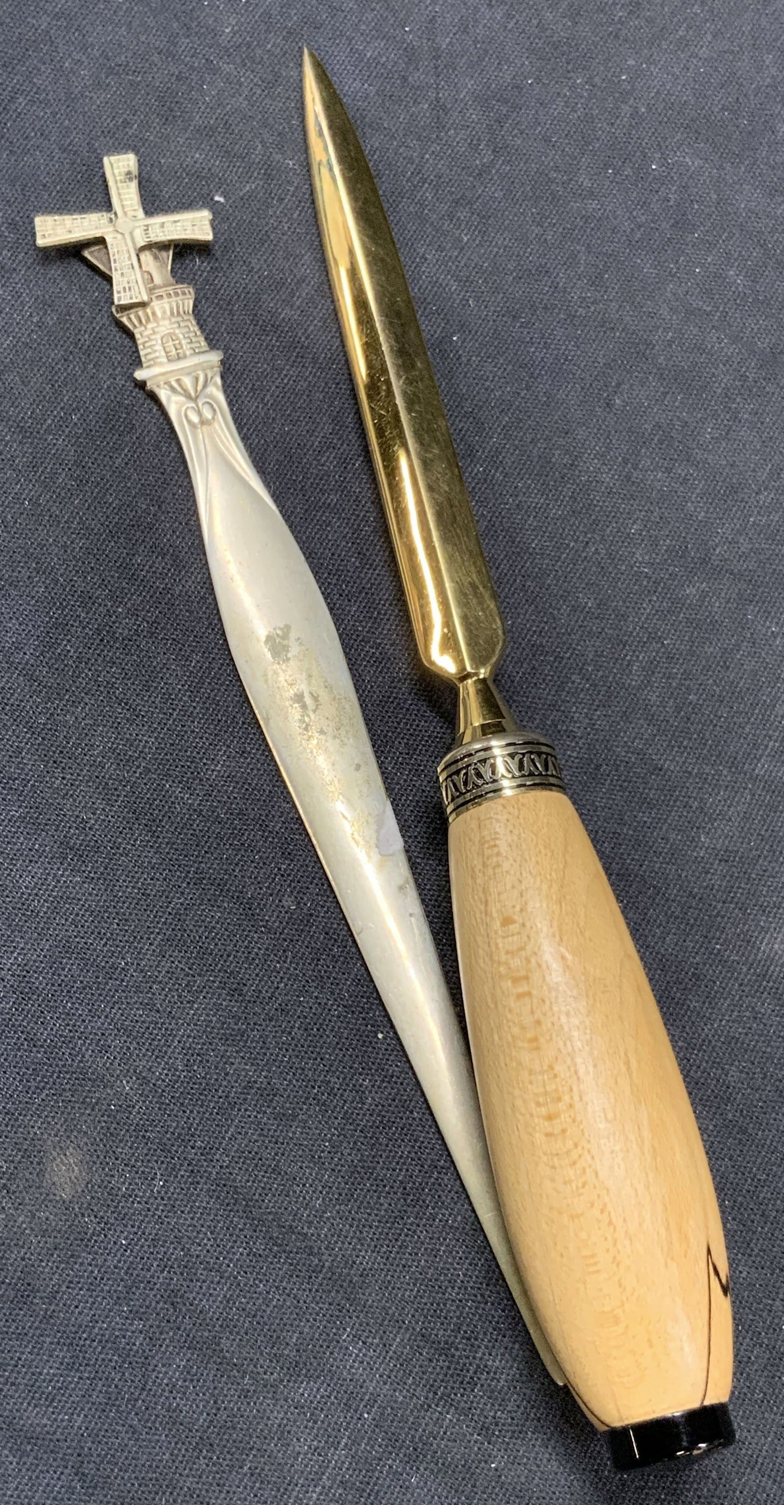 Lot 2 Silver Plate & Brass Letter Openers: Lot of 2 letters openers. 1 marked Demet with a windmill on handle, the other is brass toned with a wooden handle. Approx 6 and 7 inches long Moderate wearing to demet opener with scratches observed o