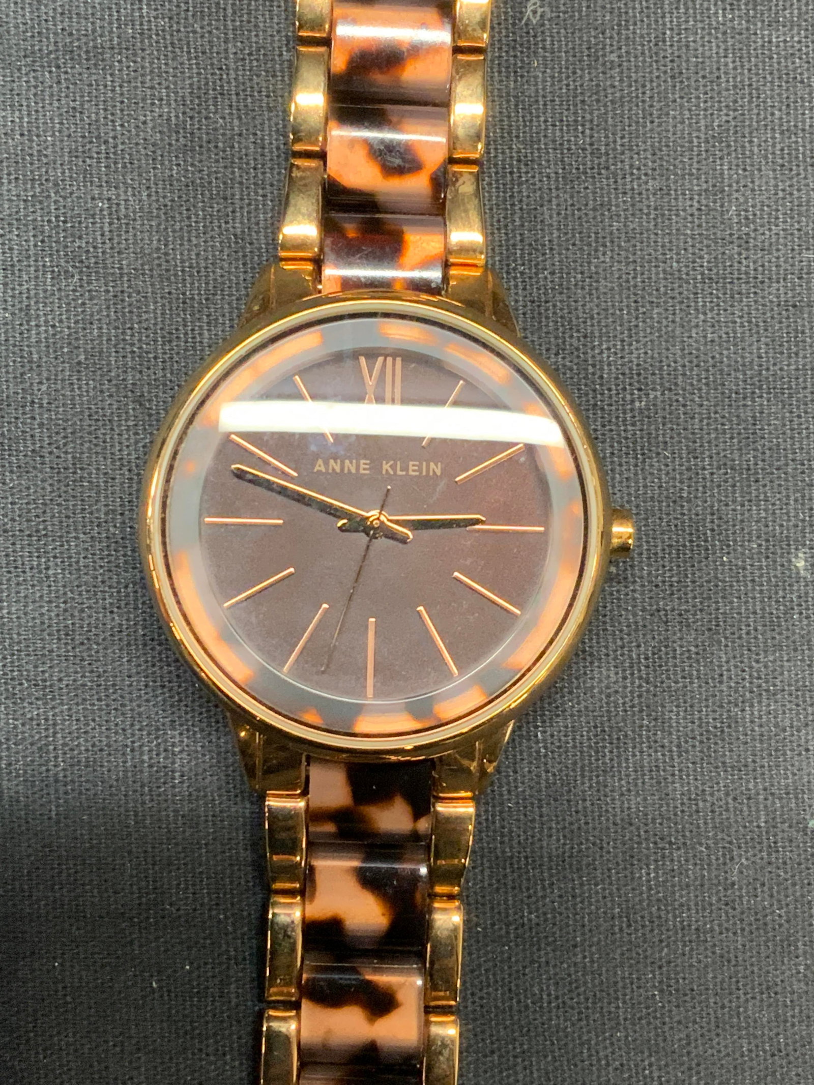 Anne Klein Gold Tone Tortoise Watch: Anne Klein gold tone stainless steel watch with marbled tortoise shell motif decoration. Signed on watch face. Measures approx. 7.25 inches long. Face measures approx. 1.5 inches wide. Not tested for