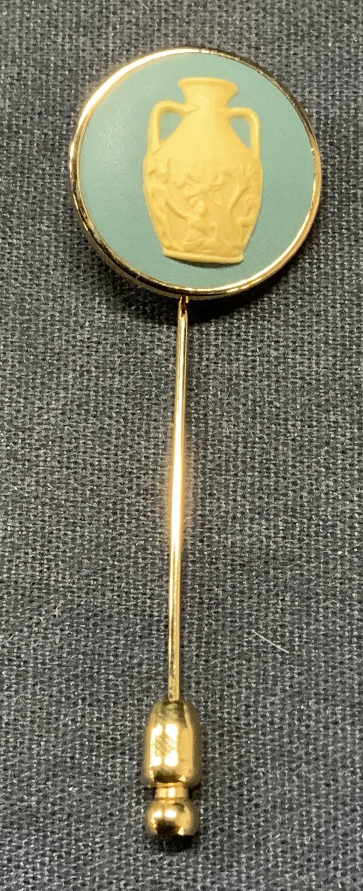 Wedgwood Jasperware Urn Stick Pin, England: Vintage Wedgwood gold tone stick pin with blue & white bas relief Jasperware pendant. Raised urn motif. Signed to underside. Made in England. Measures approx. 2.25 inches long. Some surface wear inclu