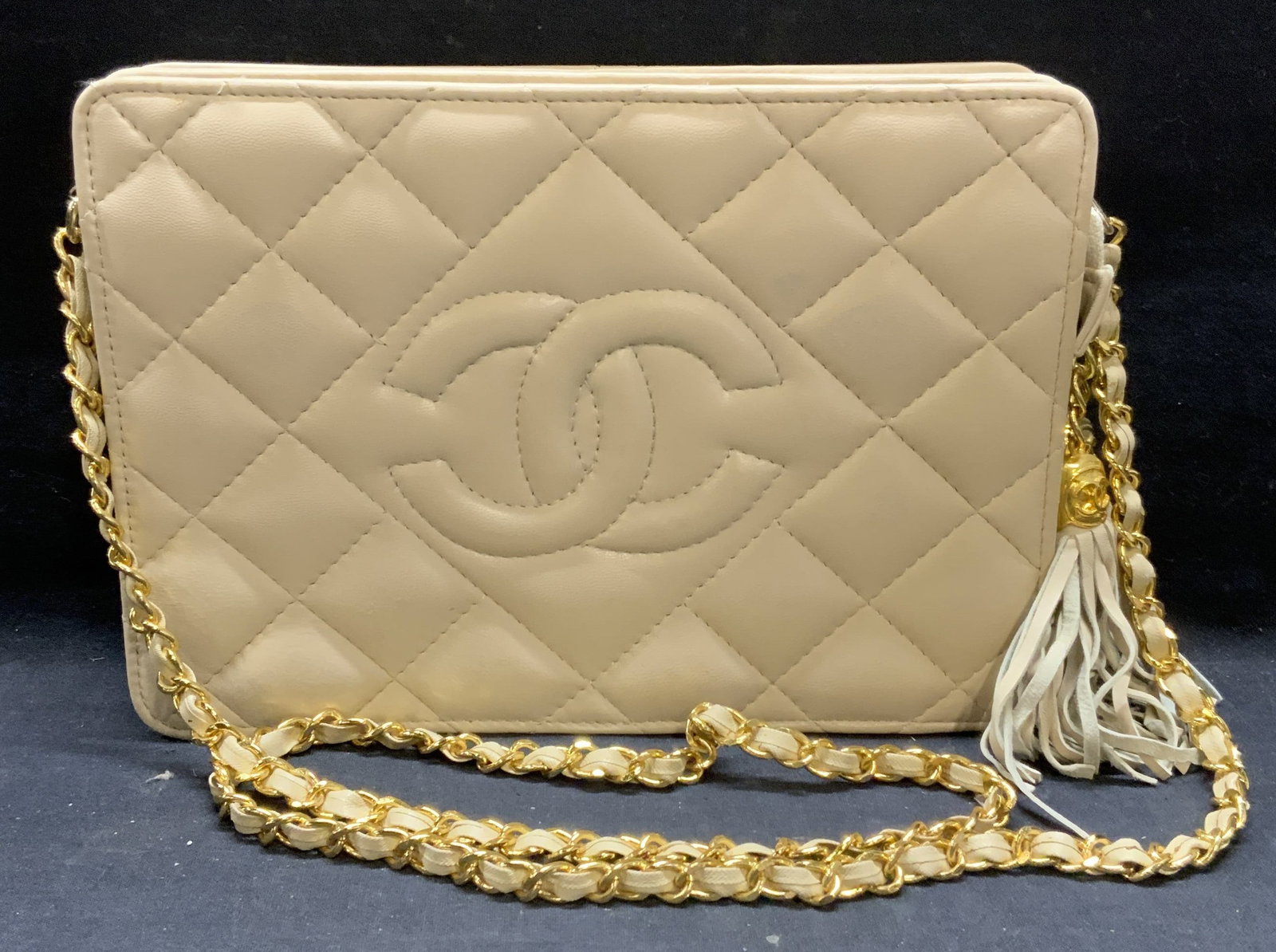 Cream Quilted Leather CC Handbag: Cream toned quilted leather handbag with interlocking C and gold tone woven chain strap. 2 zippered compartment and 1 interior zippered pocket. Measures approx. 7.5 x 1.5 x 10.5 inches. Some wear to l