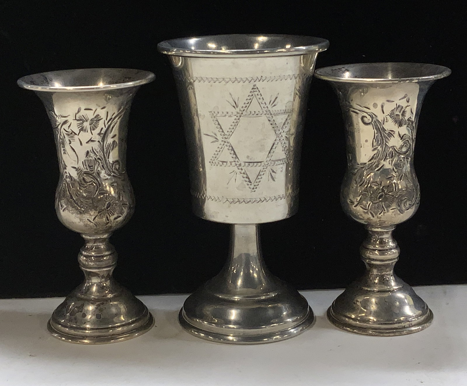 Lot 3 Sterling Sil & Plated Kiddish Cups: 2.27 ozt. Pair of repousse vintage sterling silver kiddish cups with floral design. measure 4 x 2 in. Marked Sterling on lower rim and have engraved names on the front., Additional Kiddish cup that is