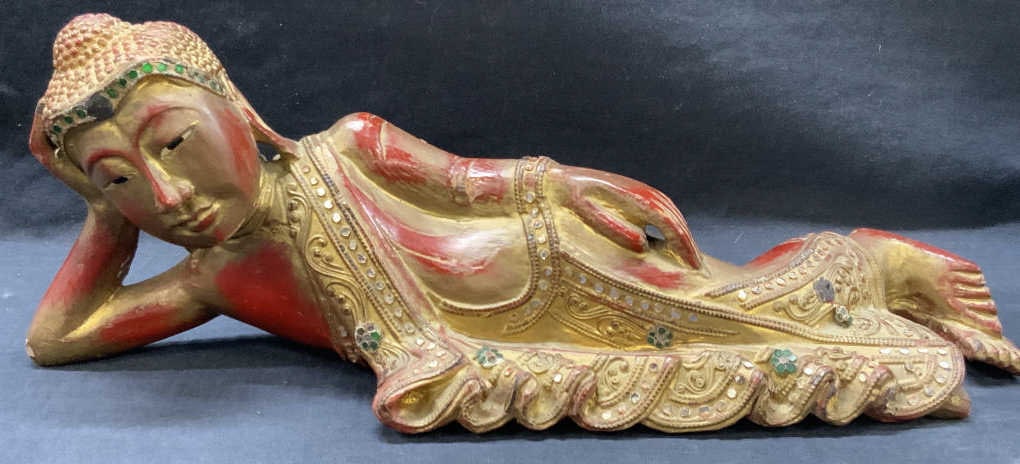 Carved Wooden Lounging Buddha Figure: Vtg carved wooden figure the lounging Buddha. Painter red with gold leafing throughout and bejeweled on areas. Approx 6 inches fall and 15 inches long. Moderate wearing to paint job and wood Buddha de