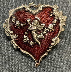 Catherine Popesco Cupid Brooch, France: Catherine Popesco antique finish silver tone heart brooch with red enamel and raised Cupid motif. Signed to underside. Made in France. Hinge pin to underside. Measures approx. 1 1/8 x 1 inches.