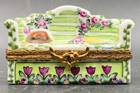 ARTORIA LIMOGES FRANCE Porcelain Sofa Pill Box: A hand painted porcelain sofa form pill box. Sofa features raised hat and bouquet to the top. Floral motifs to the sides. Opens with gold tone metal hinge hardware. Interior features hand painted