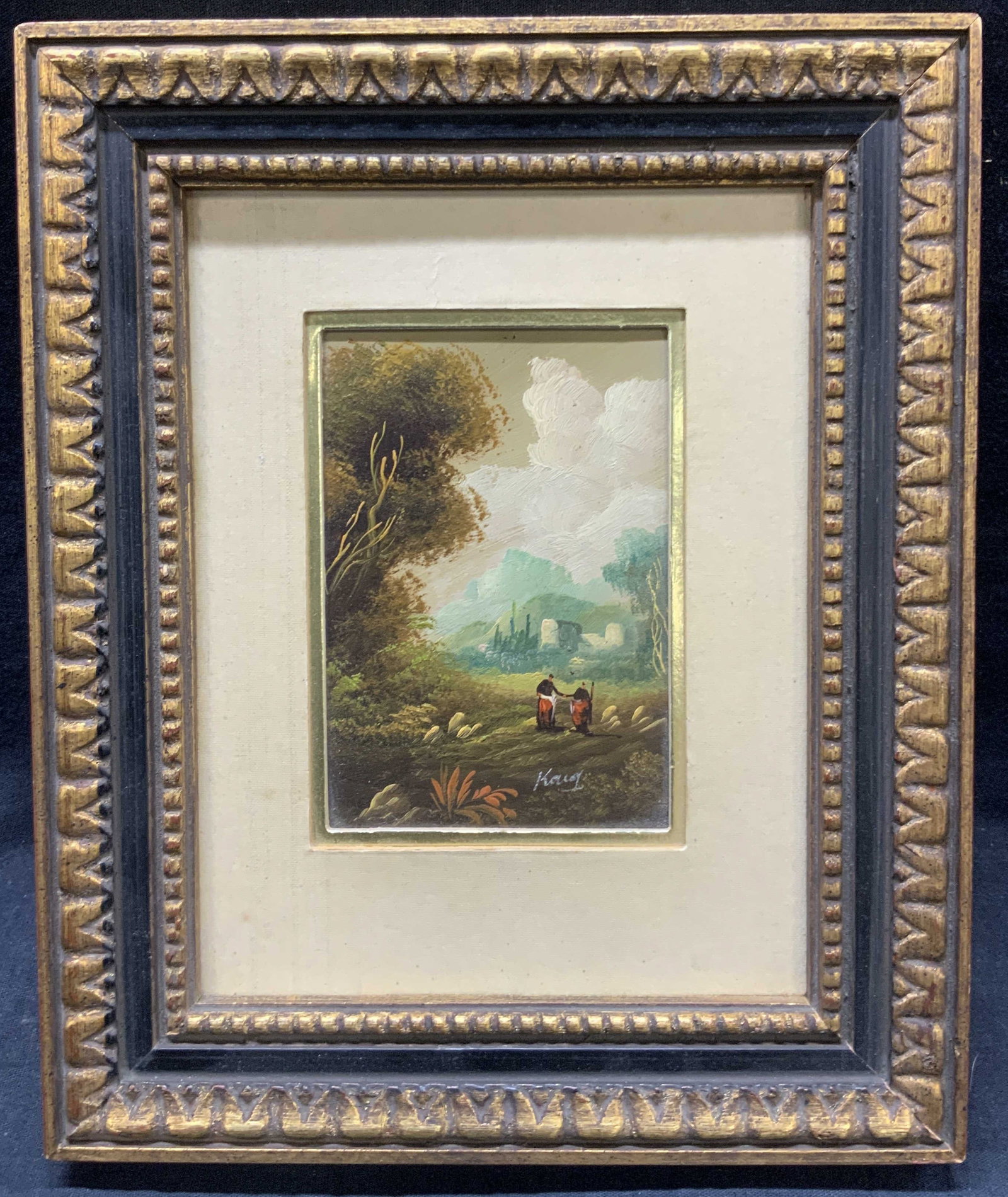 Sgd Landscape Oil Painting On Board: Signed on lower corner, possibly Keuoy Depicts a landscape painting with two people walking the grass lands with a city in the distance. Framed in a gold leafed wooden frame with carvings on exterior 
