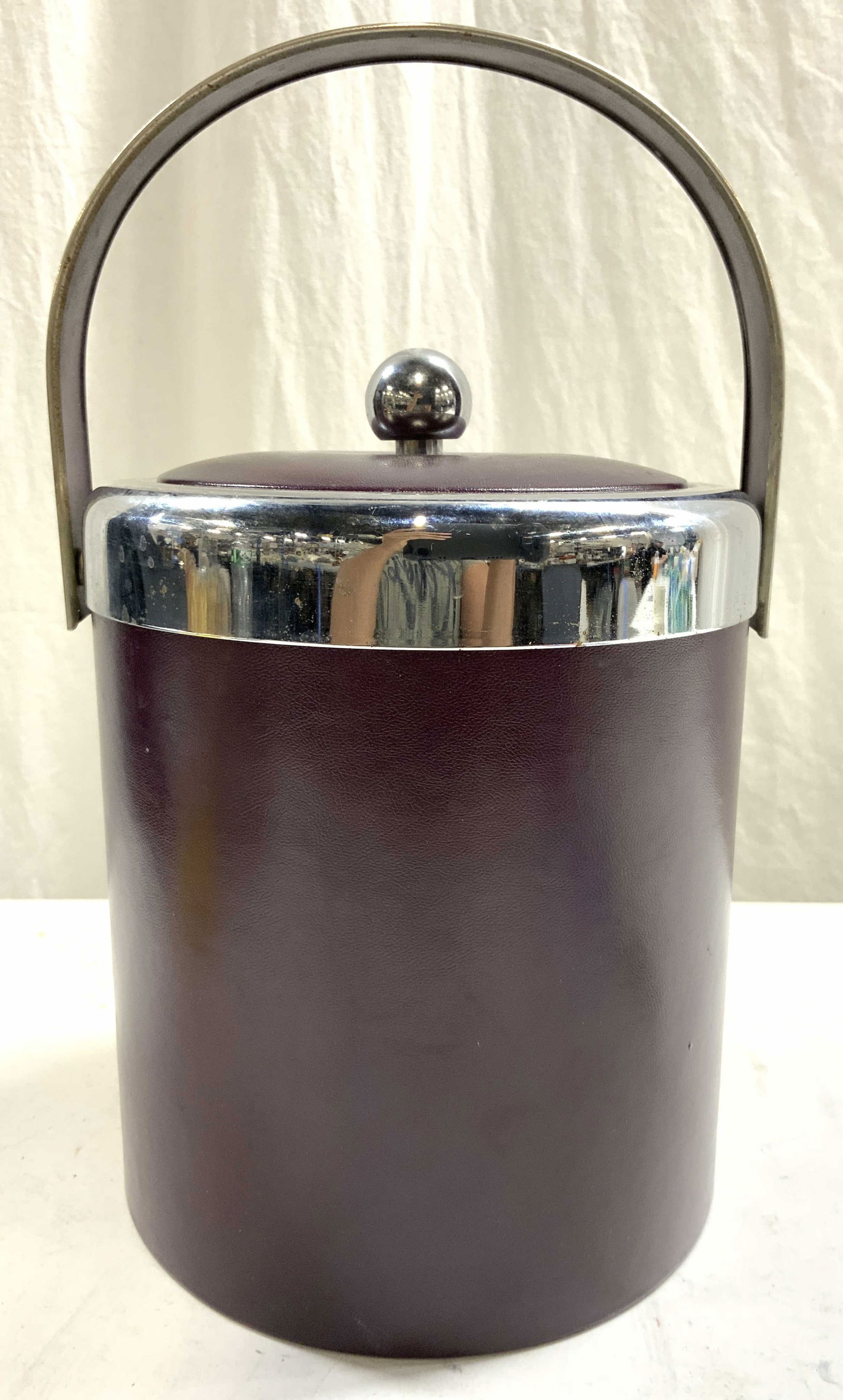 GEORGES BRIARD Pebbled Leather & Metal Ice Bucket: Underside is marked GEORGES BRIARD. Ice bucket is metal and pebbled leather. Leather areas are dark maroon toned. Ice bucket has arch form handle. Bucket includes lid. Lid has spherical shaped knob st