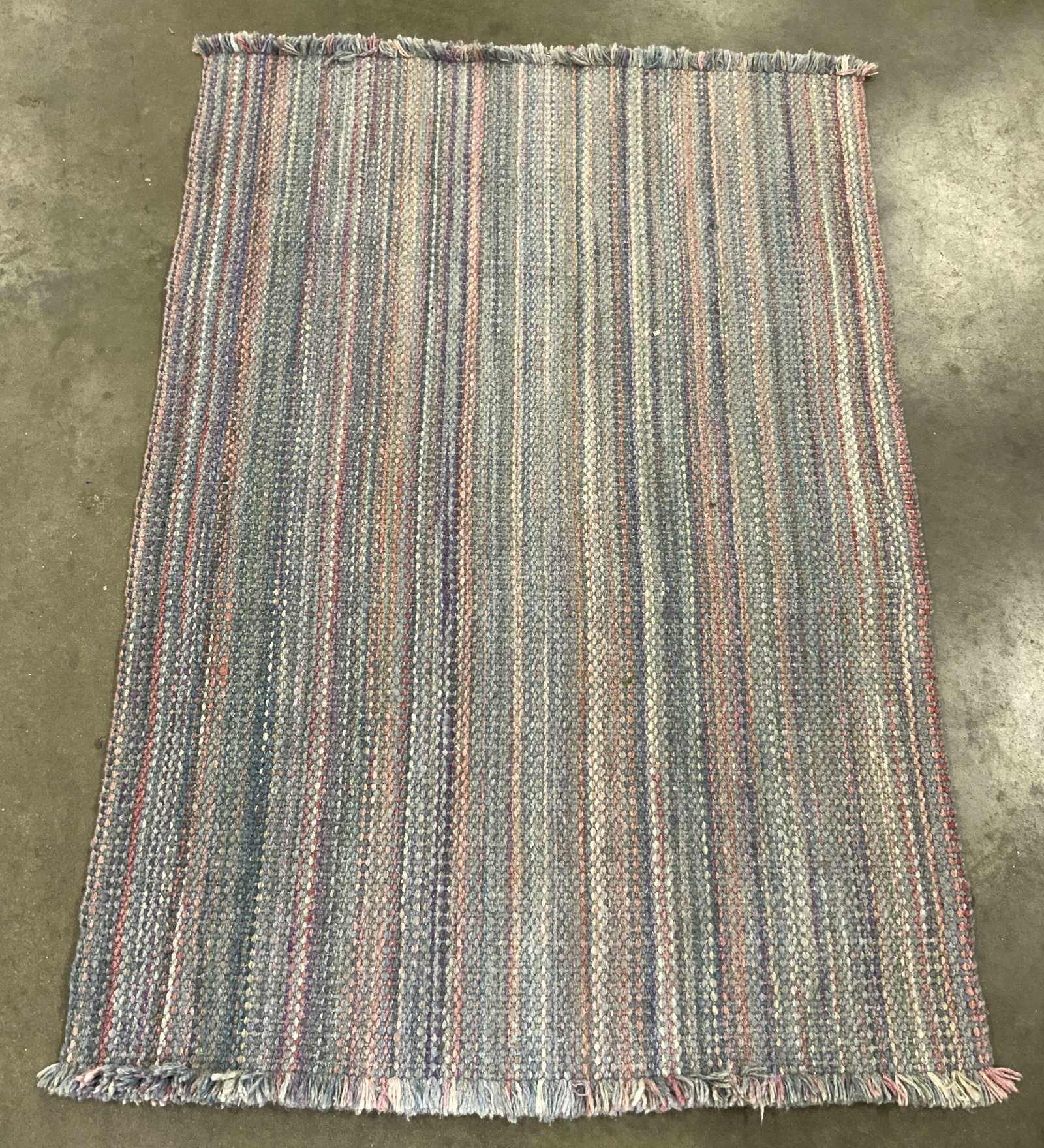 Vintage Woven Wool Rug W Fringes: Rug is vintage. Piece is woven, possibly be hand. Rug has various tones. Piece has fringes at edges. Rug measures approximately 64 inches long 43 inches wide. Rug, woven rug, wool rug, fringed rug, ar