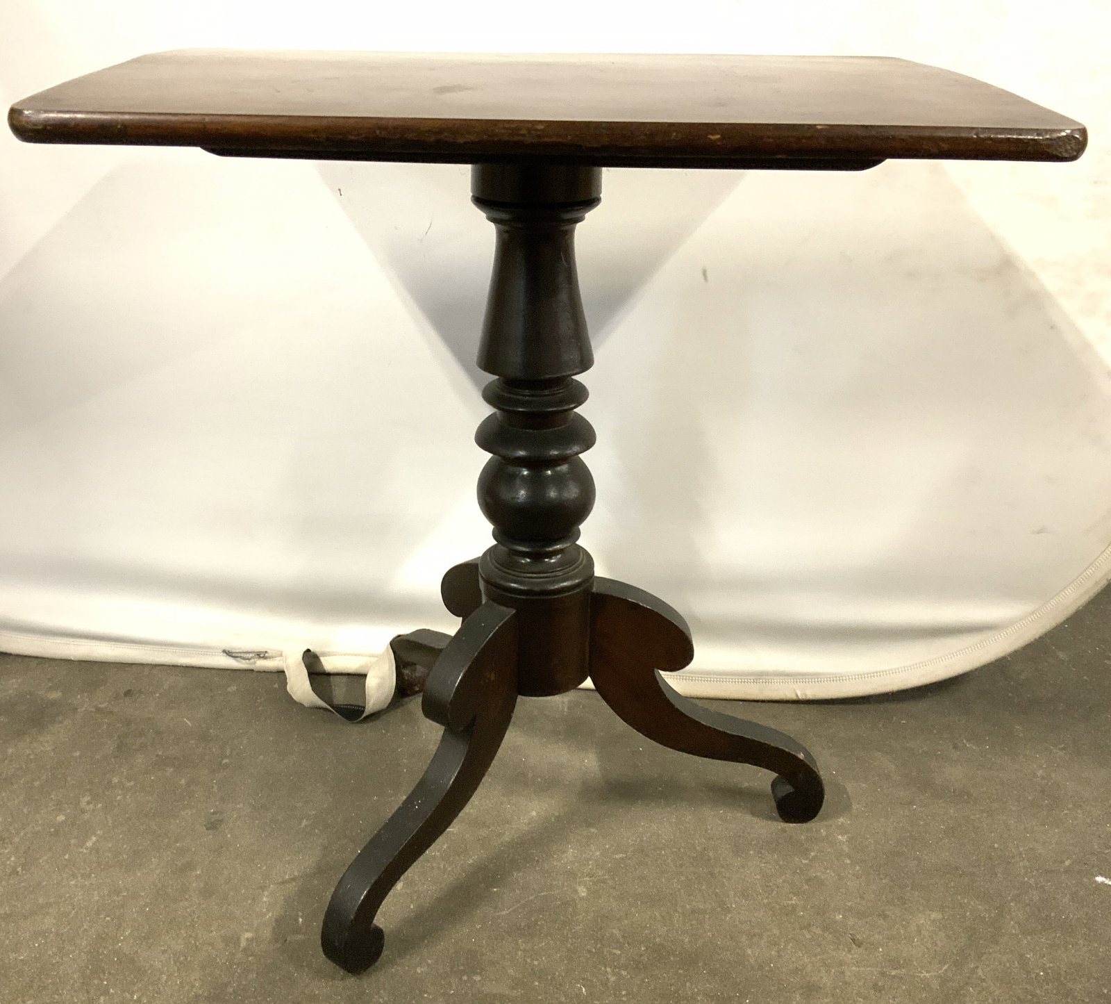 Antique Wooden Tilt Top Pedestal Table: Table is antique and wooden. Piece has tilt top and pedestaled base with three curled feet & turned support. Table is brown toned. Table measures approximately 28 inches tall 27 inches wide 18 inches 