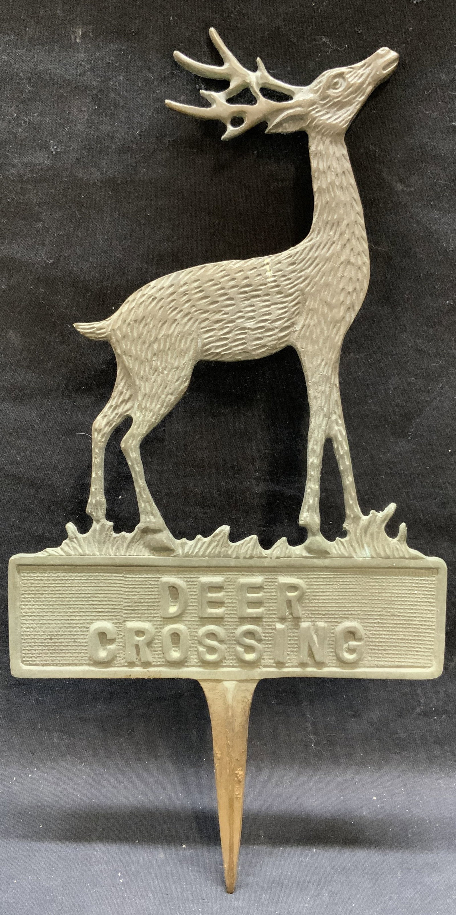 Vintage Deer Crossing Verdigris Lawn Ornament: Vintage Deer Crossing lawn ornament. Cast metal with verdigris green patina. Textured deer motif with lettering. Measures approx. 16 x 8.25 inches. Piece has weight. Some surface wear including scratc