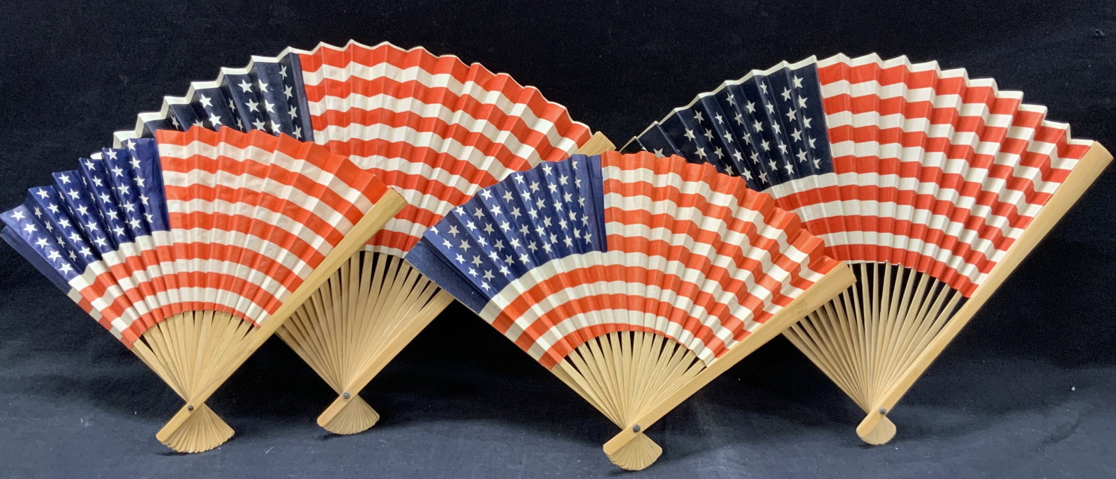 Lot 4 American Flag Paper Fans: Lot of 4 American flag red white and blue fans with light toned wooden frames. Ranging in sizes. From 10 inches long and 8 inches long Minor wearing to fans and paper. American paper fans. Paper fans.