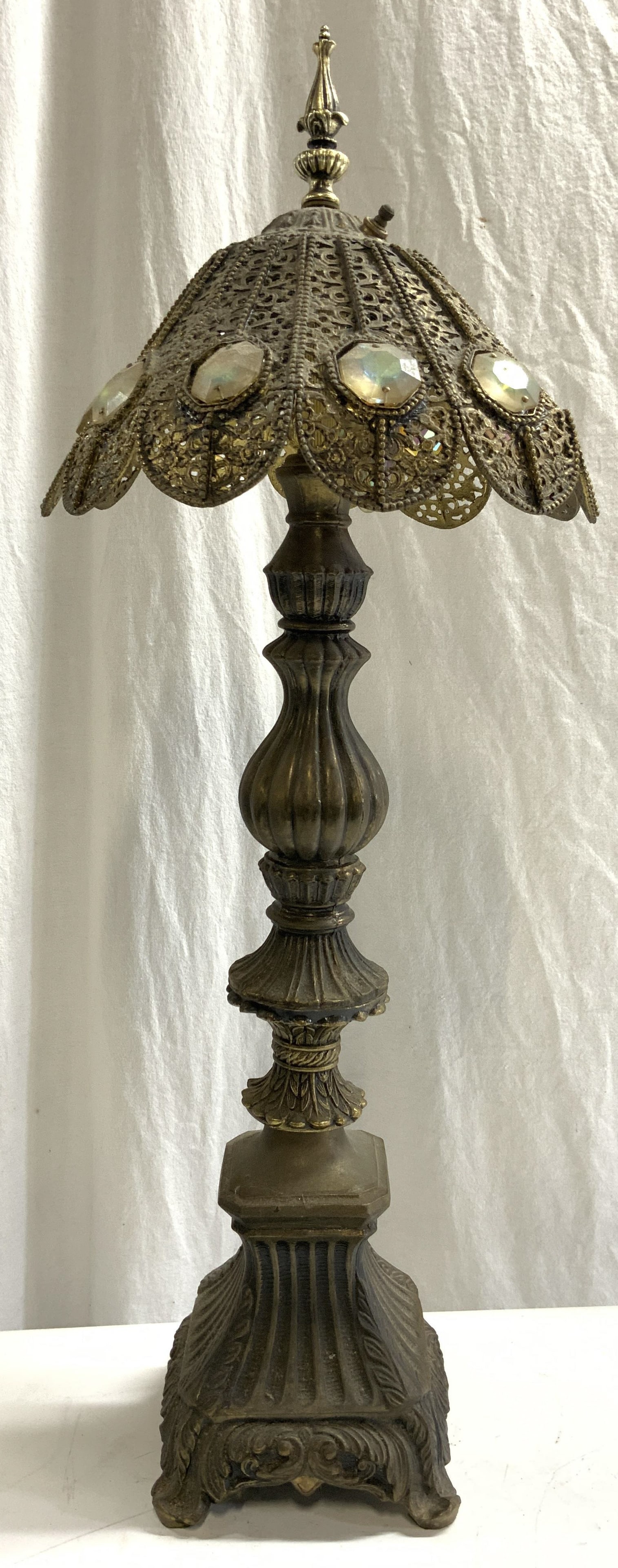Vintage Moroccan Filigree Shade Brass Lamp: Lamp is vintage. Piece has filigree style shade with pierced detail. Lamp is brass. Piece has scroll & leaf detail. Piece has gilt metal finial & twist switch on top of shade. Lamp is footed. Shade ha