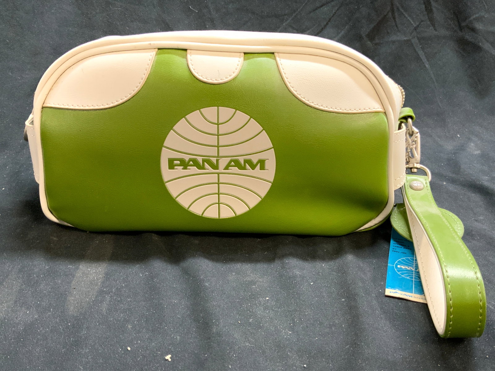 PAN AM Leather Travel Bag Green & White W Tag: Bag has PAN AM Logo on one side, reads PAN AM on other. Piece also has Pan Am Logo bag ornament. Bag has wrist loop. Piece measures approximately 12 inches long 6 inches tall. Interior has patch. Bag,