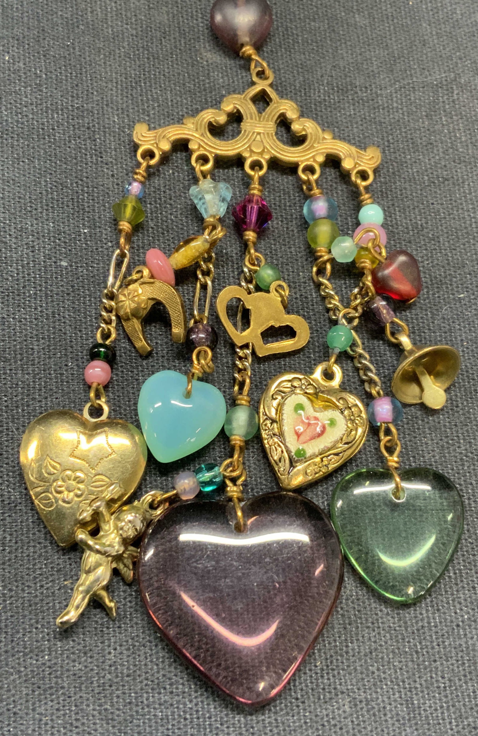 Lucy Isaacs NYC Gold Tone Pendant Necklace: Lucy Isaacs NYC gold tone pendant necklace with heart shaped glass pendants. Signed on hang tag. Drop length approx. 15.5 inches. Pendant drop length approx. 4.25 inches. Some surface wear including s