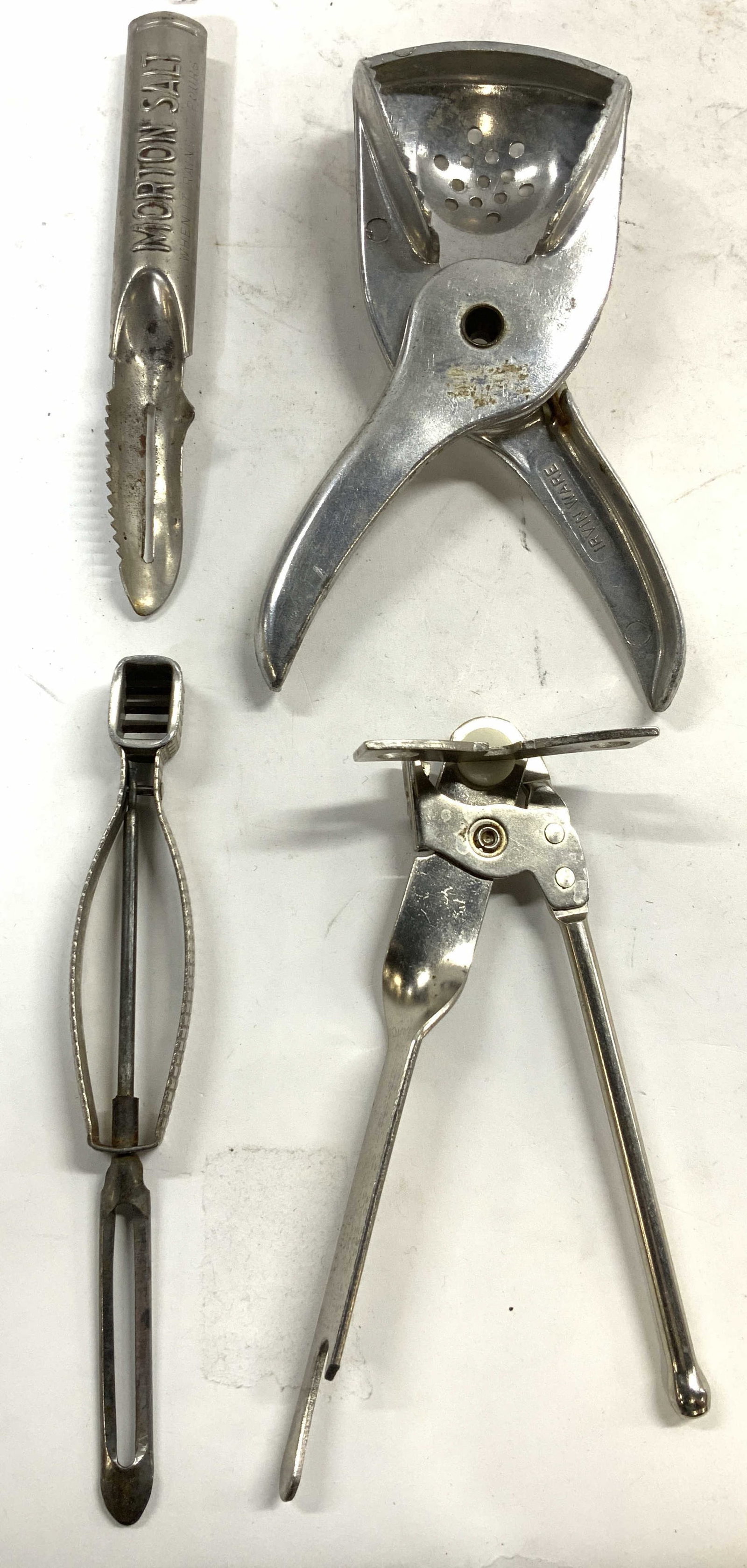 Lot 4 Metal Vintage Kitchenware Accessories: Lot includes 1 IRVIN WARE Citrus juicer, 1 can opener, 1 potato peeler, & 1 MORTON SALT peeler. Each piece is silver toned and metal. Each piece is vintage. Citrus juicer measures approximately 6.5 in