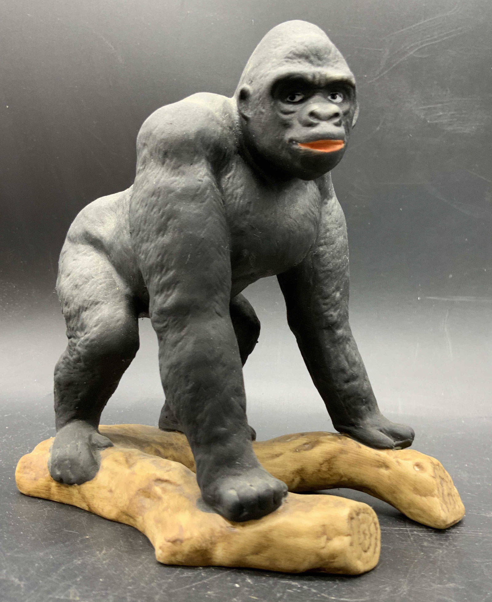 ALDON Vintage Porcelain Gorilla Figural Japan: A vintage porcelain gorilla figural. The gorilla is depicted resting on a brown hued branch. Underside sticker reads FINE GRAINED PORCELAIN CREATED BY ALDON, MADE IN JAPAN. Measures approx. 5H x 5W in