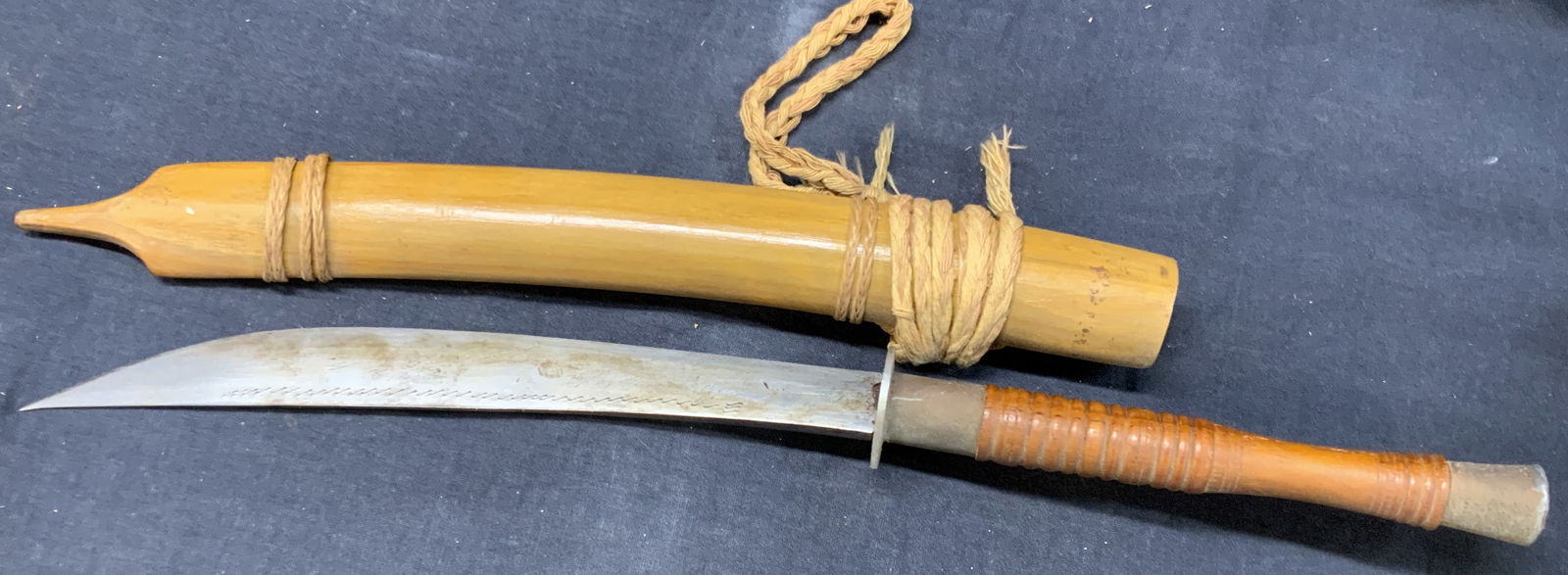 Vtg Steel Curved Thai Dagger: Vintage Thai dagger made with steel etched blade and bamboo made sheath with a wooden handle. Approx 19 inches long total length. Handle is approx 6 inches long and blades are approx 9 inches long. Ev