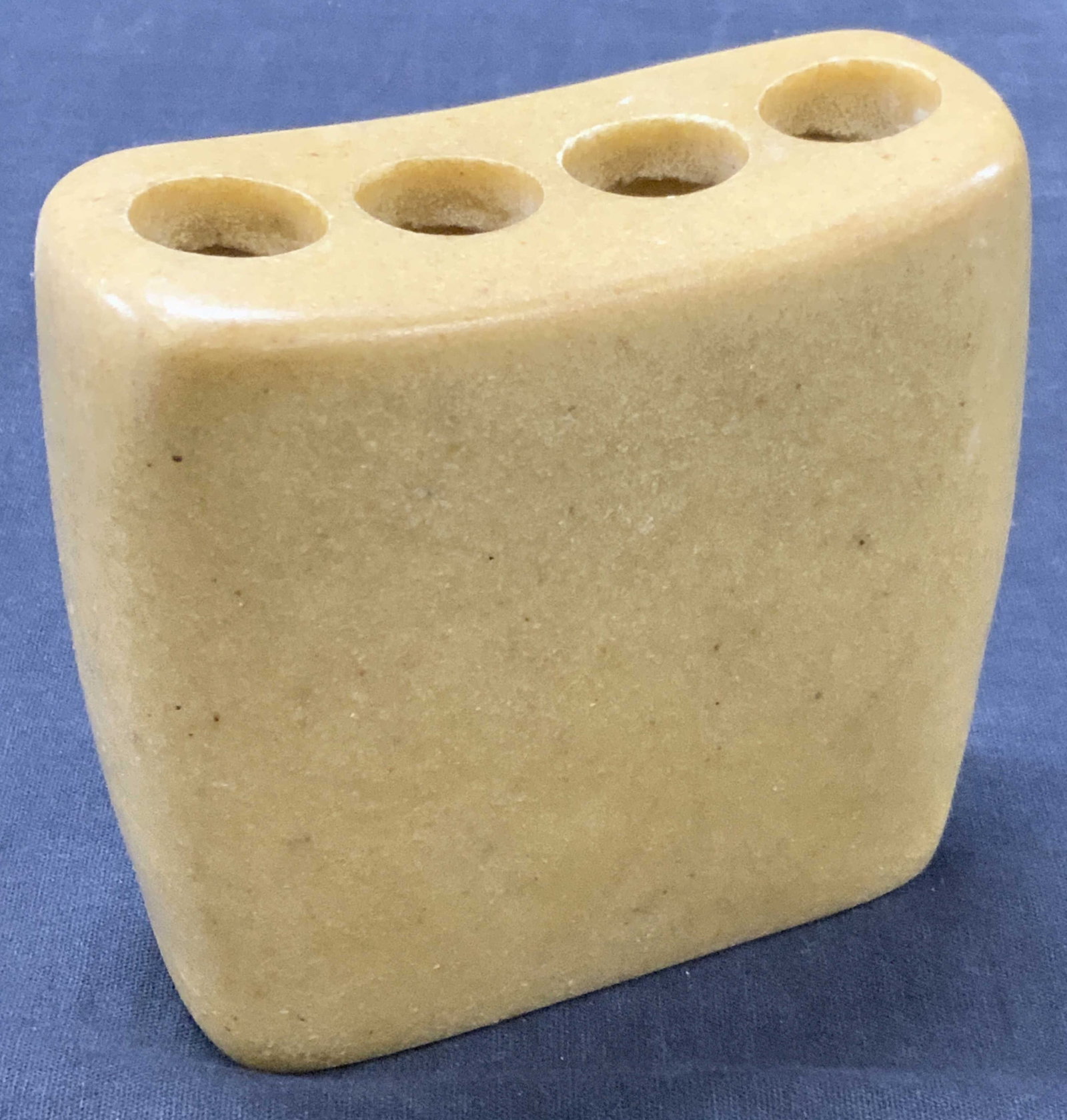 Carved Stone Vessel: Carved stone vessel / bud vase / tooth brush holder, made of yellow toned stone and with four circle cut outs on top. Approx 4 inches tall and 4 inches wide. Minor wearing to stone due to age and use 