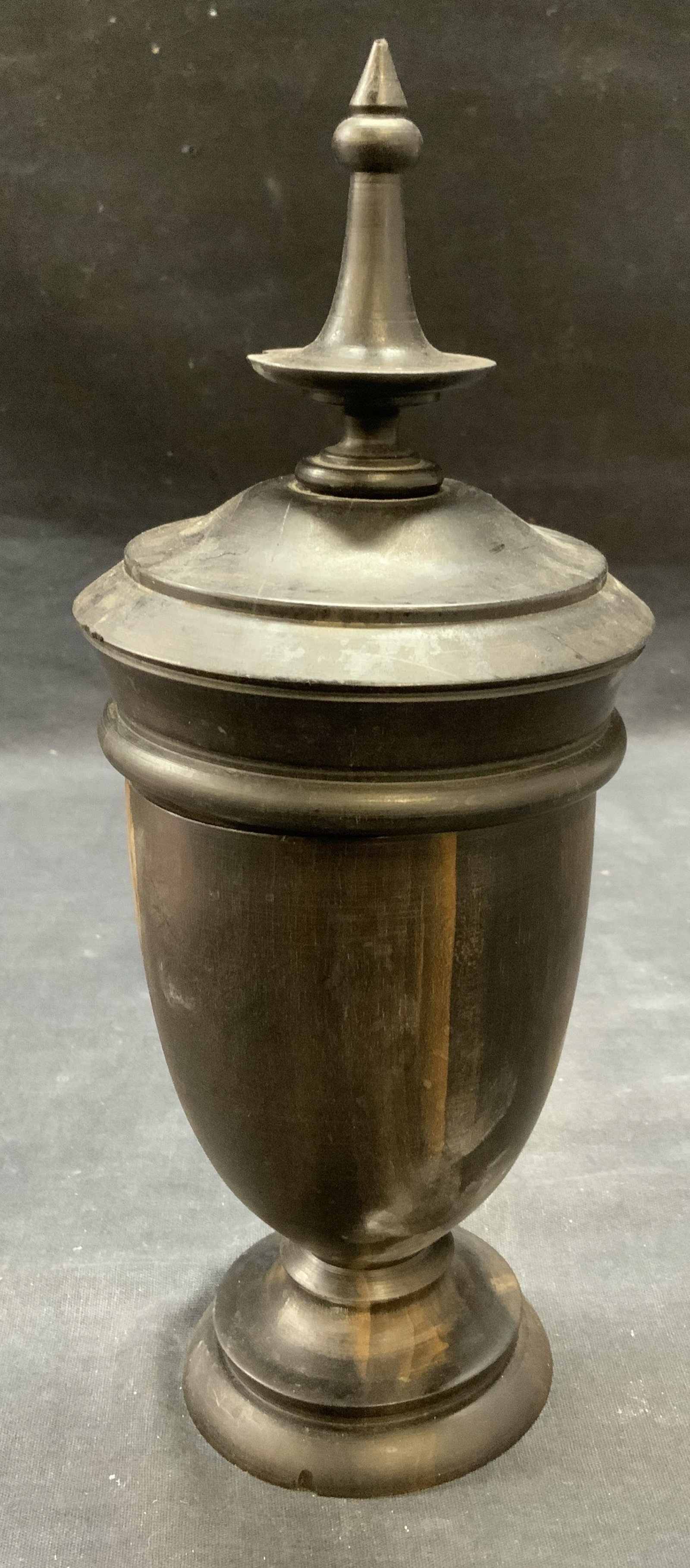 Carved Wood Covered Urn Vessel: Carved dark brown wood urn vessel with lid. Measures approx. 4.25 x 10.5 inches. Some surface wear including scratching and chipping observed. Urn, urn vessel, covered urn, lidded urn, wood urn, decor