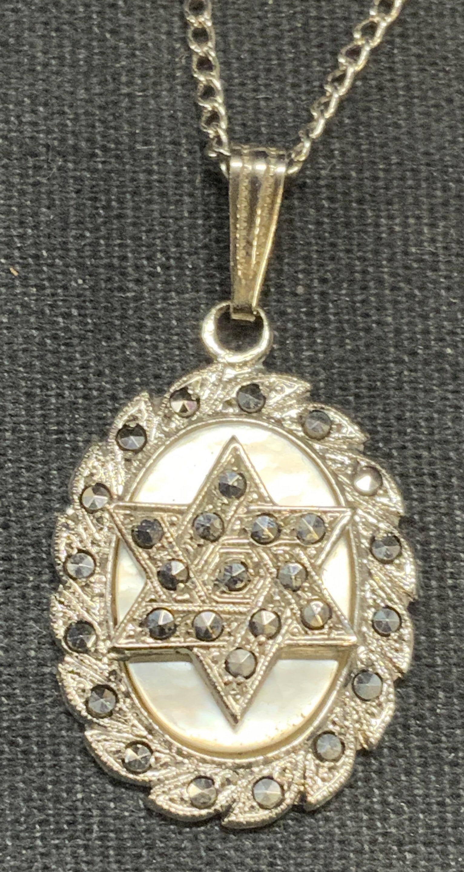 Sterling Silver Star of David Pendant Necklace: Sterling silver necklace with Star of David pendant and mother of pearl and marcasite decoration. Marked sterling on clasp and pendant. Drop length approx. 7.5 inches. Total weight 5.4 grams. Some sur