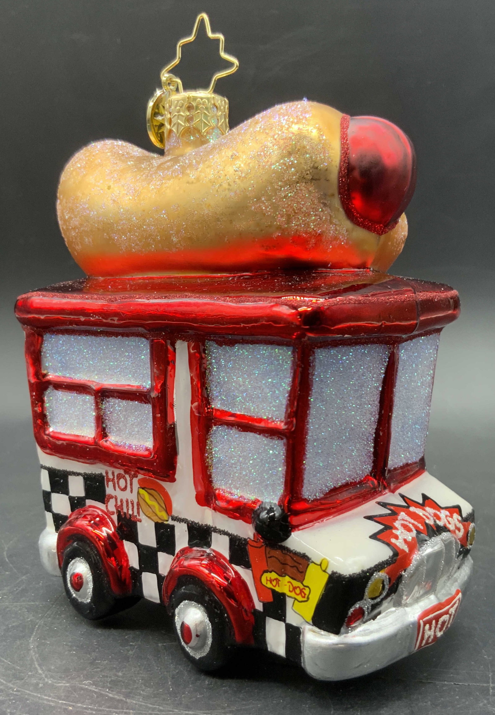 CHRISTOPHER RADKO Hot Diggity Dog Ornament, Bx: A boxed Christopher Radko Hot Diggity Dog hot dog truck ornament. Crafted from glass. Gold tone metal topper. Charm on ornament reads CHRISTOPHER RADKO. Comes in original box. Box measures approx. 5.5